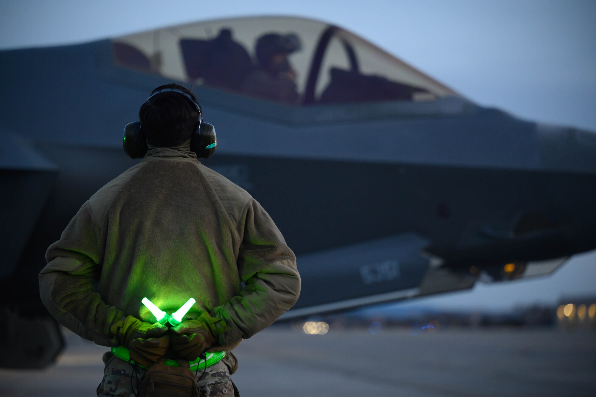 A crew chief looks towards an aircraft before takeoff.