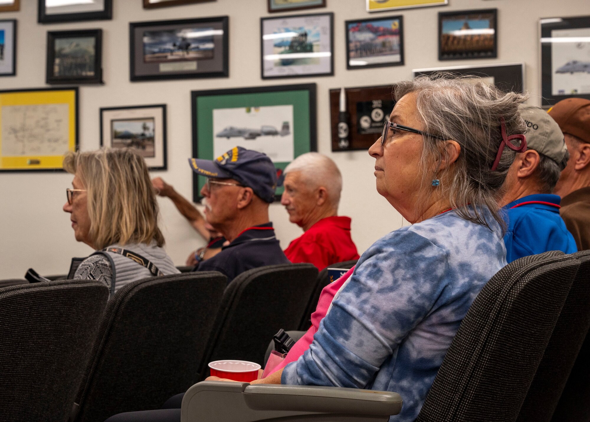 A group of people sit in rows listening to a speaker.