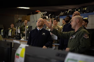 U.S. Air Force Col. Steven Niewiarowski, right, 607th Air Operations Command chief of combat operations, stands in the AOC in a flight suit as points to a screen while briefing Air Force Chief of Staff Gen. David Allvin and Chief Master Sgt. of the Air Force David Flosi who are both in blues during a visit at Osan Air Base, Republic of Korea, Oct. 17, 2024.