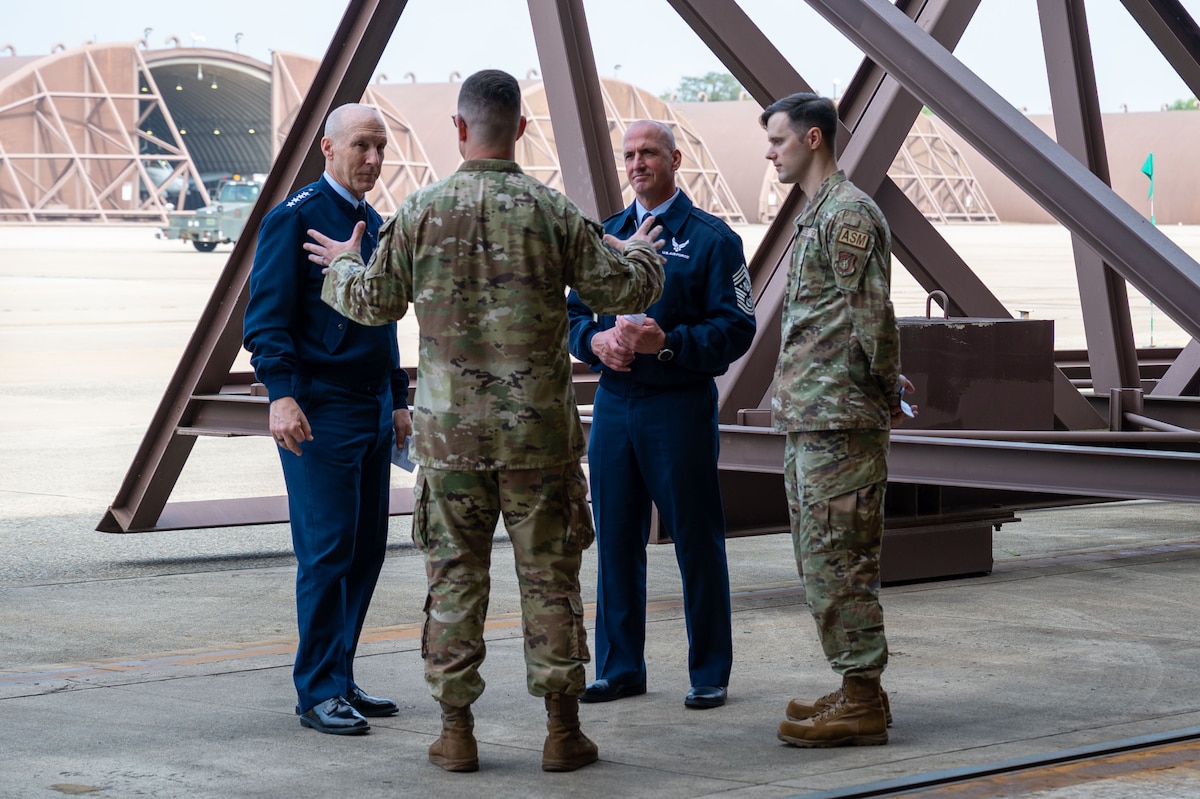 Chief of Staff of the Air Force Gen. David Allvin and Chief Master Sgt. of the Air Force David Flosi, in blues receive a brief from two Airmen in OCPs at the entrance of an aircraft hangar about the paint barn at Osan Air Base, Republic of Korea, Oct. 17, 2024.