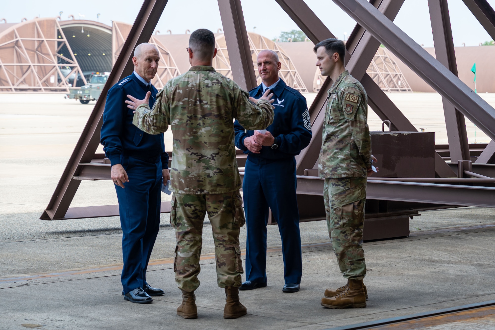 Chief of Staff of the Air Force Gen. David Allvin and Chief Master Sgt. of the Air Force David Flosi, in blues receive a brief from two Airmen in OCPs at the entrance of an aircraft hangar about the paint barn at Osan Air Base, Republic of Korea, Oct. 17, 2024.