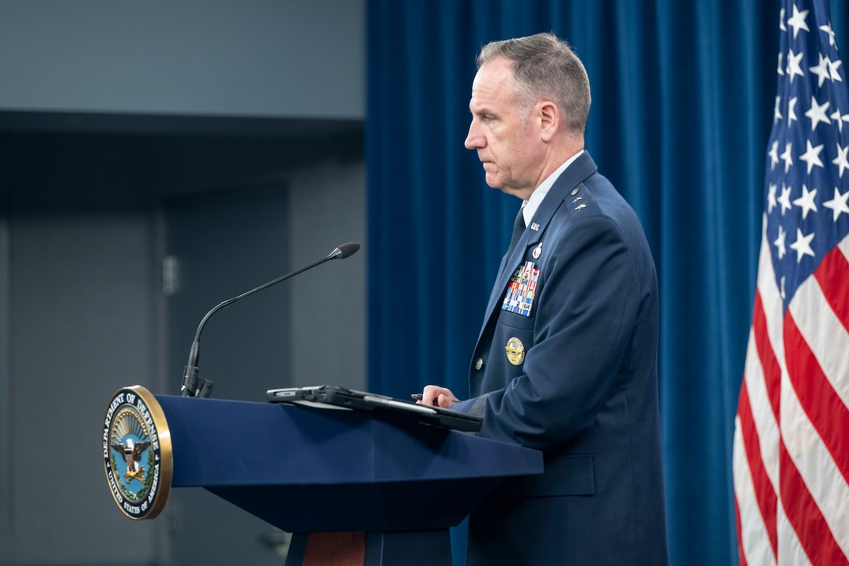 A sideview of a man speaking from a podium.