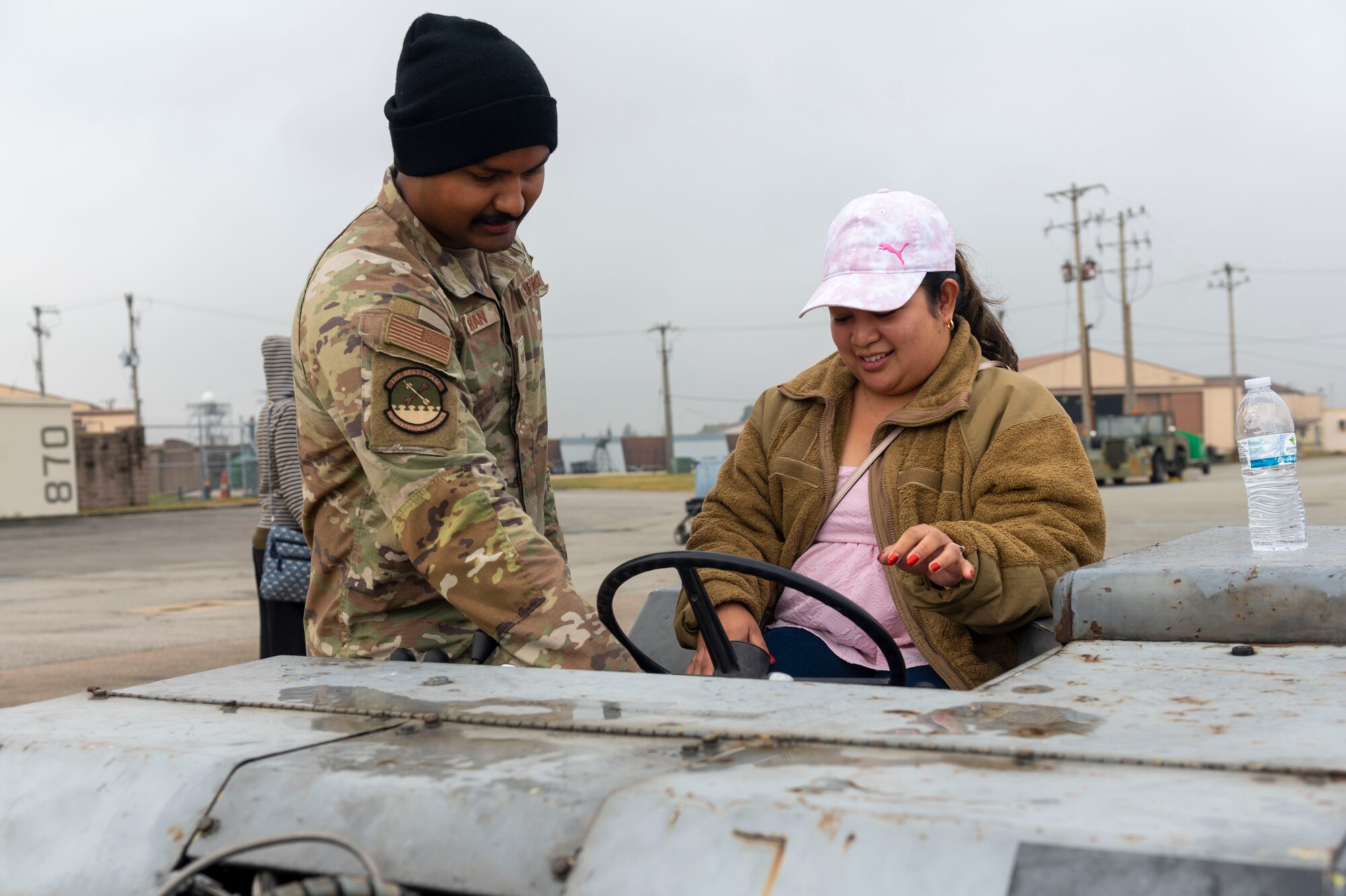 U.S. Air Force Senior Airman Marcu Balkaran, 51st Maintenance Group vehicle weapons loader, teaches Rhegerose Gamueda, Osan spouse, how to drive a bomb loader vehicle during the Osan Spouse Immersion Tour at Osan Air Base, Republic of Korea, Oct. 16, 2024. The Aerospace Ground Equipment flight controls, modernizes and repairs AGE units worth $23 million. This flight also supports the base infrastructure as required and provides transient aircraft support every day. (U.S. Air Force photo by Senior Airman Kaitlin Frazier)
