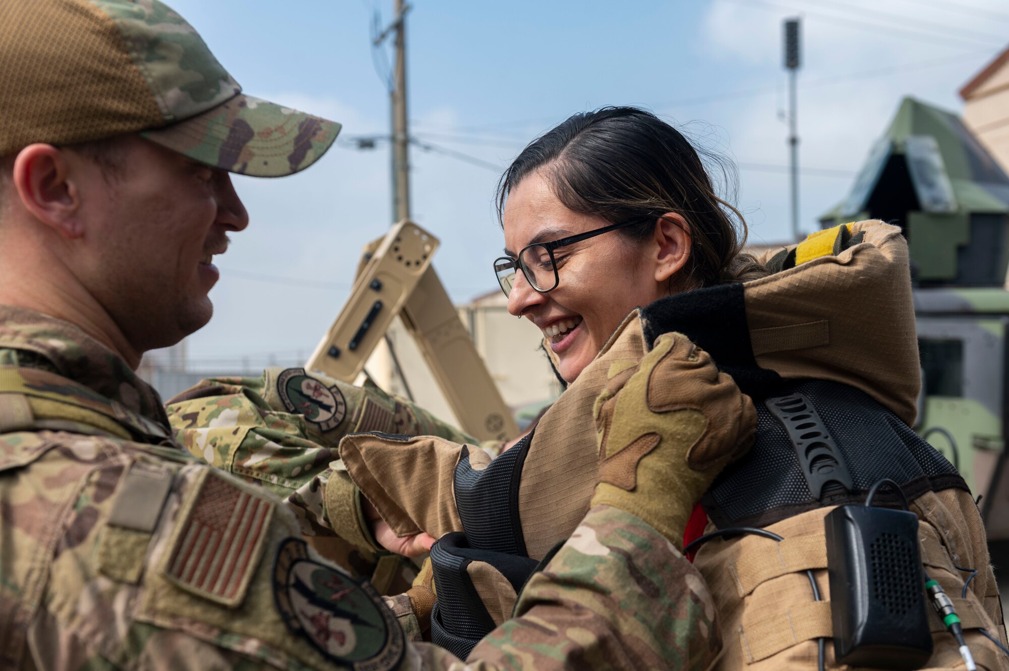 U.S. Air Force Senior Airman Cameron Keyes, 51st Civil Engineer Squadron Explosive Ordnance Disposal flight team member, helps Crystal Sanchez, Osan spouse, put on a bomb suit during the Osan Spouse Immersion Tour at Osan Air Base, Republic of Korea, Oct. 16, 2024. The Explosive Ordnance Disposal flight conducts and supports 10 mission areas and its primary mission is to clear and defend the airfield from explosive hazards. (U.S. Air Force photo by Senior Airman Kaitlin Frazier)