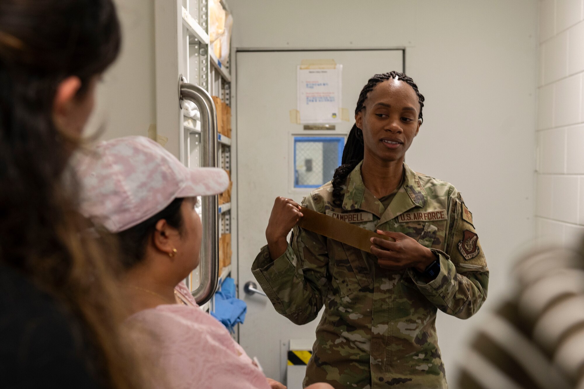 U.S. Air Force Senior Airman Christina Campbell, 51st Medical Group dental technician, showcases M9 tape during the Osan Spouse Immersion Tour at Osan Air Base, Republic of Korea, Oct. 16, 2024. During real-world scenarios, M9 tape would change colors to alert Airmen of the presence of chemical contaminants in the air. (U.S. Air Force photo by Senior Airman Kaitlin Frazier)