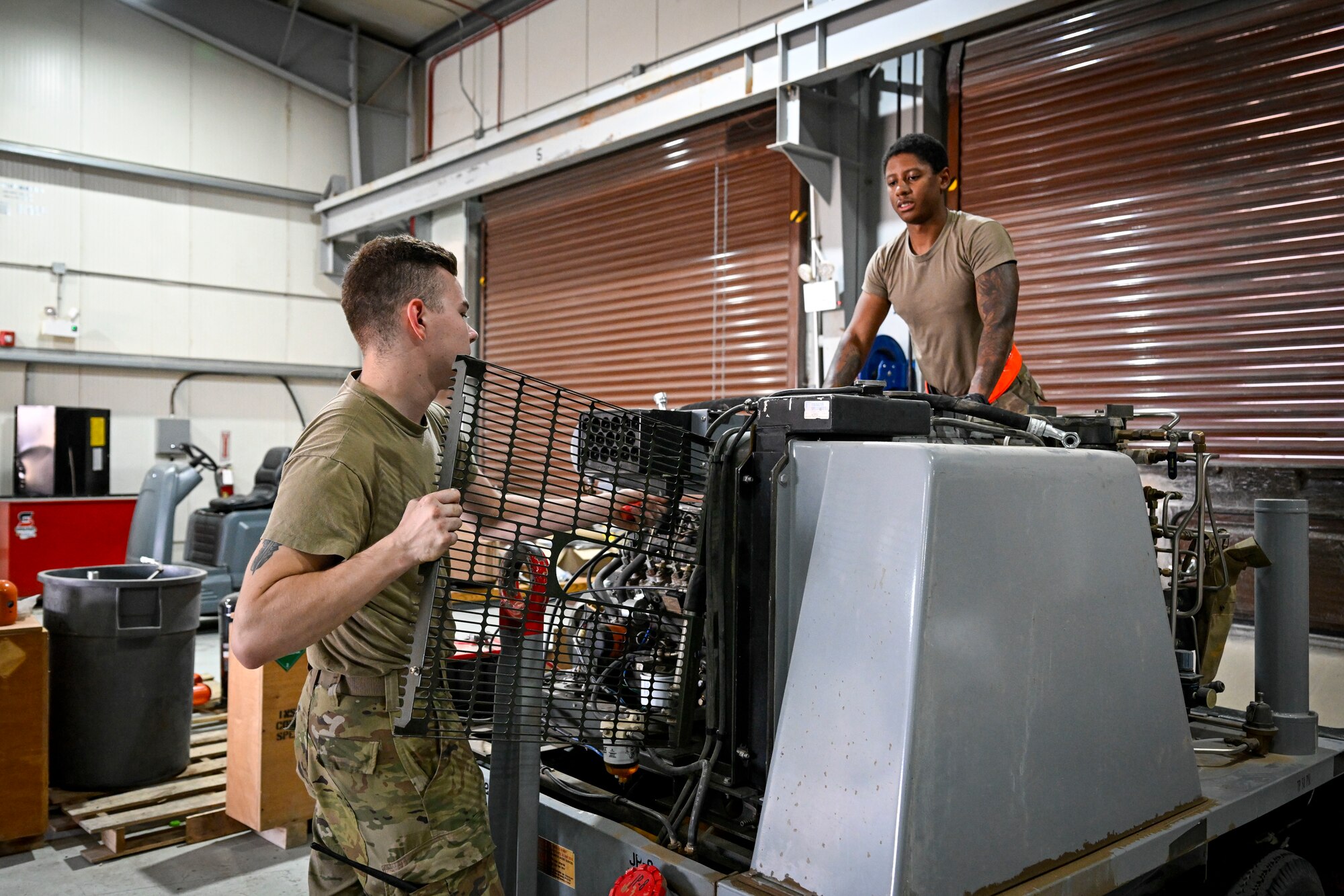 Two Airmen work on a piece of equipment.