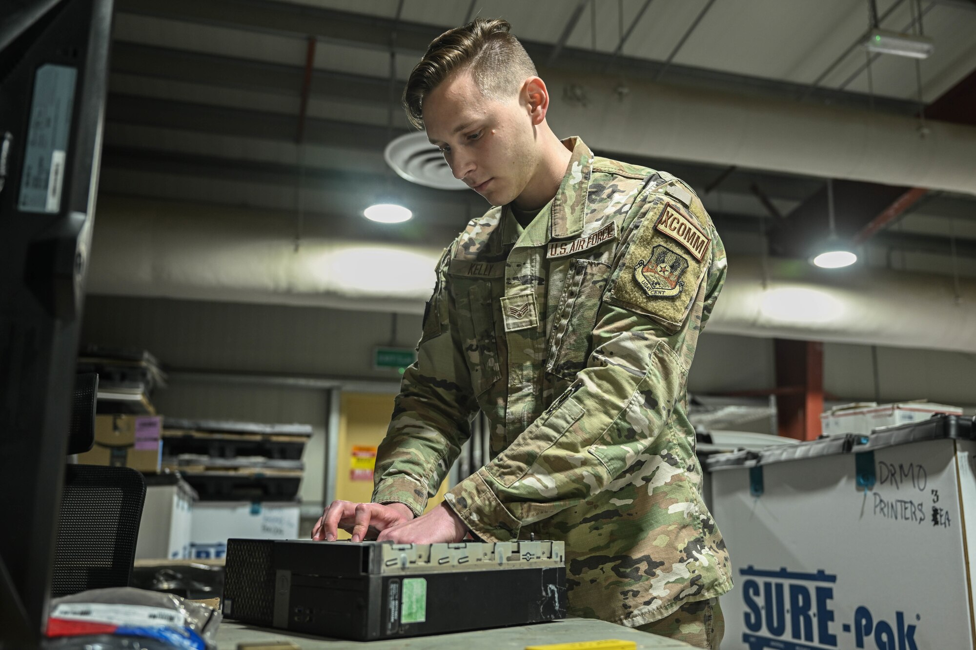 A man in uniform works on a disassembled computer.