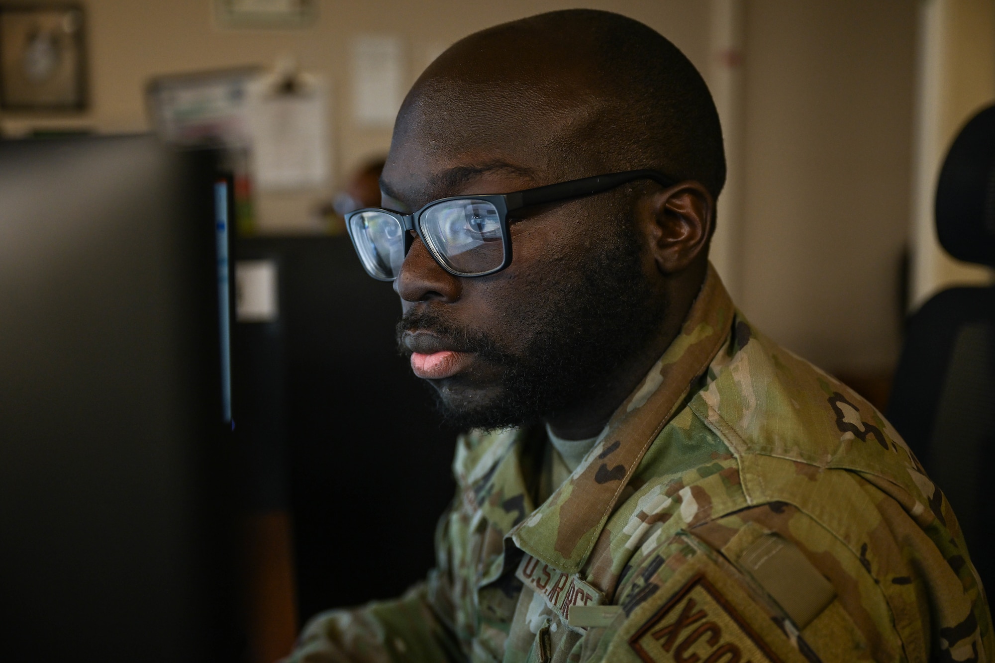 A man in uniform looks at a computer.
