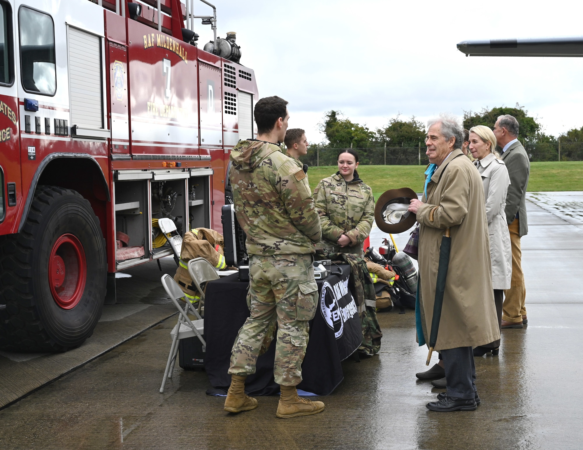 U.S. Airmen assigned to the 100th Civil Engineer Squadron Fire Department and Emergency Management, chat with guests at a static display as part of a special event for Vice Lord-Lieutenants, Deputy Lieutenants, High Sheriffs, Royal Air Force representatives and other invited guests from the local community at Royal Air Force Mildenhall, England, Oct. 9, 2024. The guests received a close-up look at a KC-135 Stratotanker, CV-22 Osprey, and MC-130 Commando II aircraft. (U.S. Air Force photo by Karen Abeyasekere)