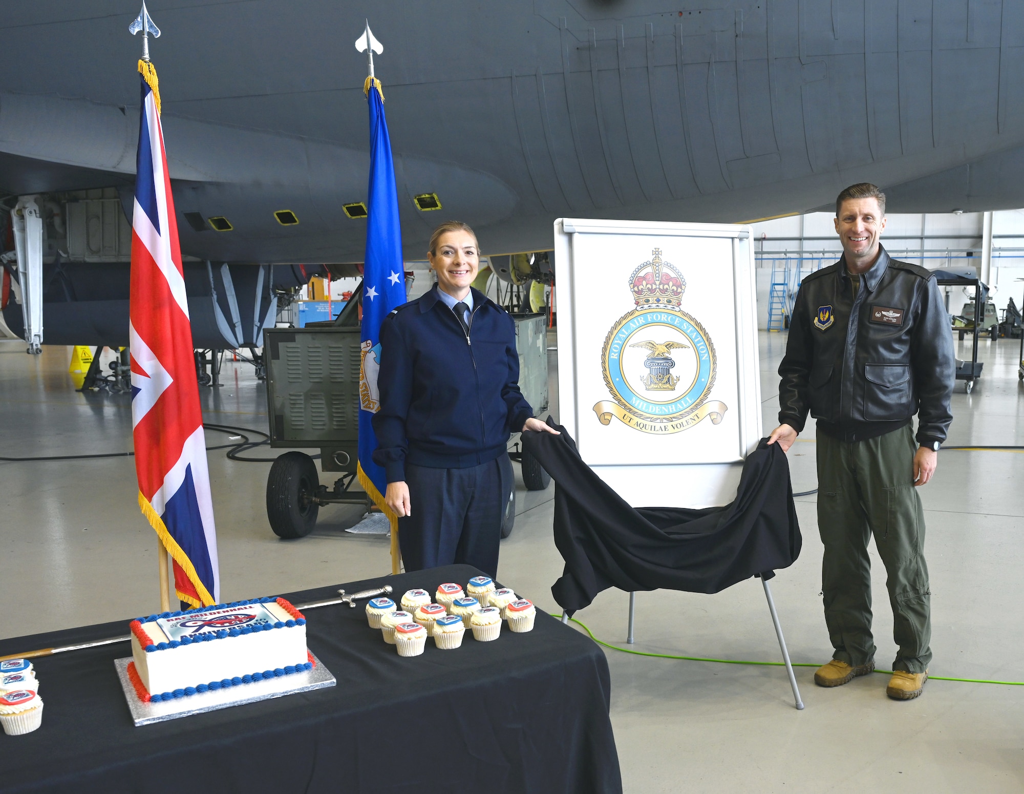 Royal Air Force Air Commodore Claire O’Grady, left, Deputy Air Officer Commanding No. 2 Group, and U.S. Air Force Col. Ryan Garlow, 100th Air Refueling Wing commander, unveil the new station crest – the Tudor Crown – at an event for Vice Lord-Lieutenants, Deputy Lieutenants, High Sheriffs, RAF representatives and other invited guests from the local community at RAF Mildenhall, England, Oct. 9, 2024. The Tudor Crown, used by HRH King Charles III, replaced the St. Edward’s Crown formerly used by HRH Queen Elizabeth II and will be placed on the tails of all 100th ARW KC-135 Stratotankers. The event also marked the 90th anniversary of RAF Mildenhall. (U.S. Air Force photo by Karen Abeyasekere)