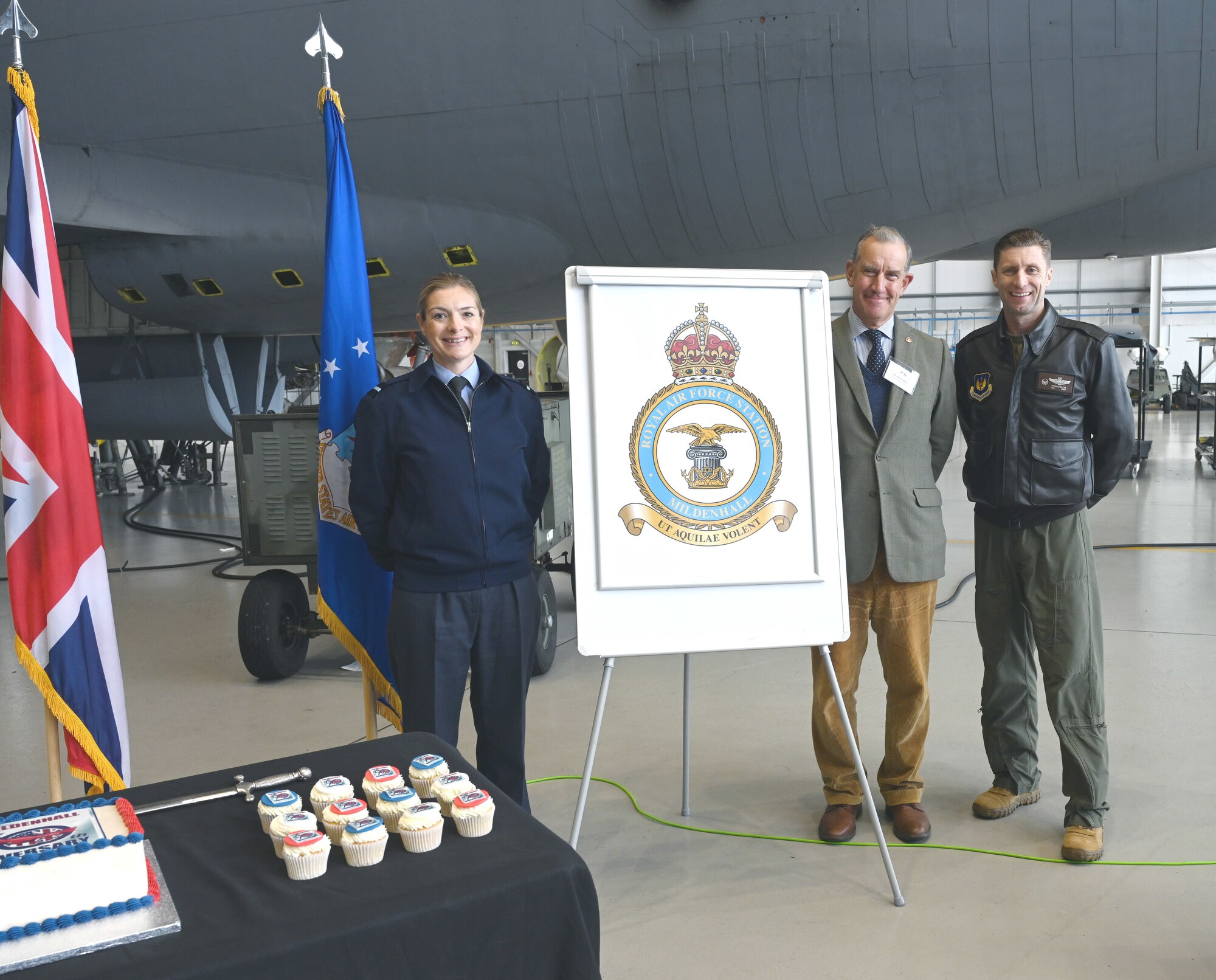 Royal Air Force Air Commodore Claire O’Grady, left, Deputy Air Officer Commanding No. 2 Group, Robert Rous, center, Vice Lord-Lieutenant of Suffolk; and U.S. Air Force Col. Ryan Garlow, 100th Air Refueling Wing commander, acknowledge the newly unveiled station crest – the Tudor Crown – at an event for Vice Lord-Lieutenants, Deputy Lieutenants, High Sheriffs, RAF representatives and other invited guests from the local community at RAF Mildenhall, England, Oct. 9, 2024. The Tudor Crown, used by HRH King Charles III, replaced the St. Edward’s Crown formerly used by HRH Queen Elizabeth II and will be placed on the tails of all 100th ARW KC-135 Stratotankers. The event also marked the 90th anniversary of RAF Mildenhall. (U.S. Air Force photo by Karen Abeyasekere)