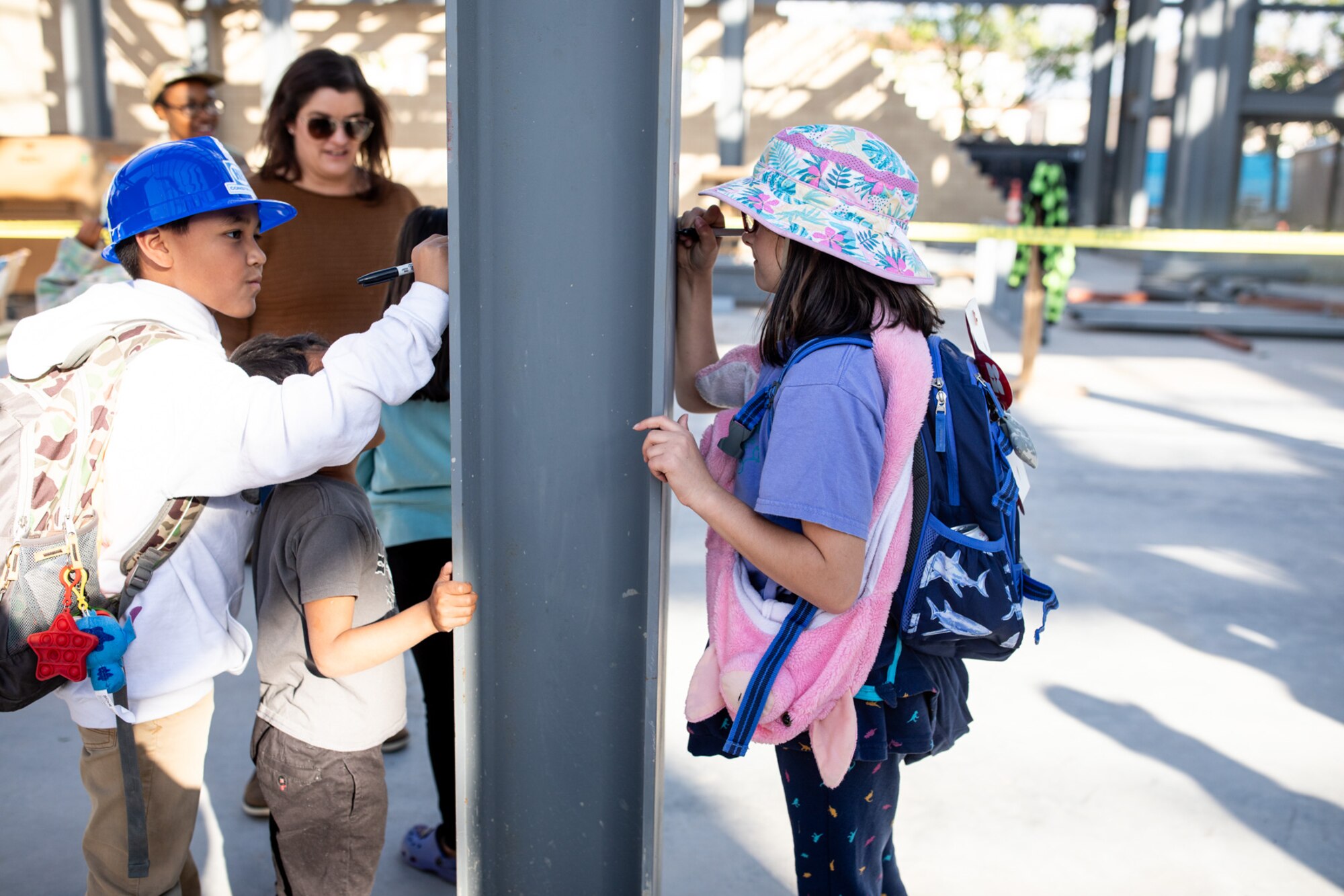 Elementary students sign steel beam at construction site for new elementary school
