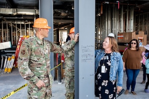 military man and civilian woman sign steel beam of newly constructed elementary school