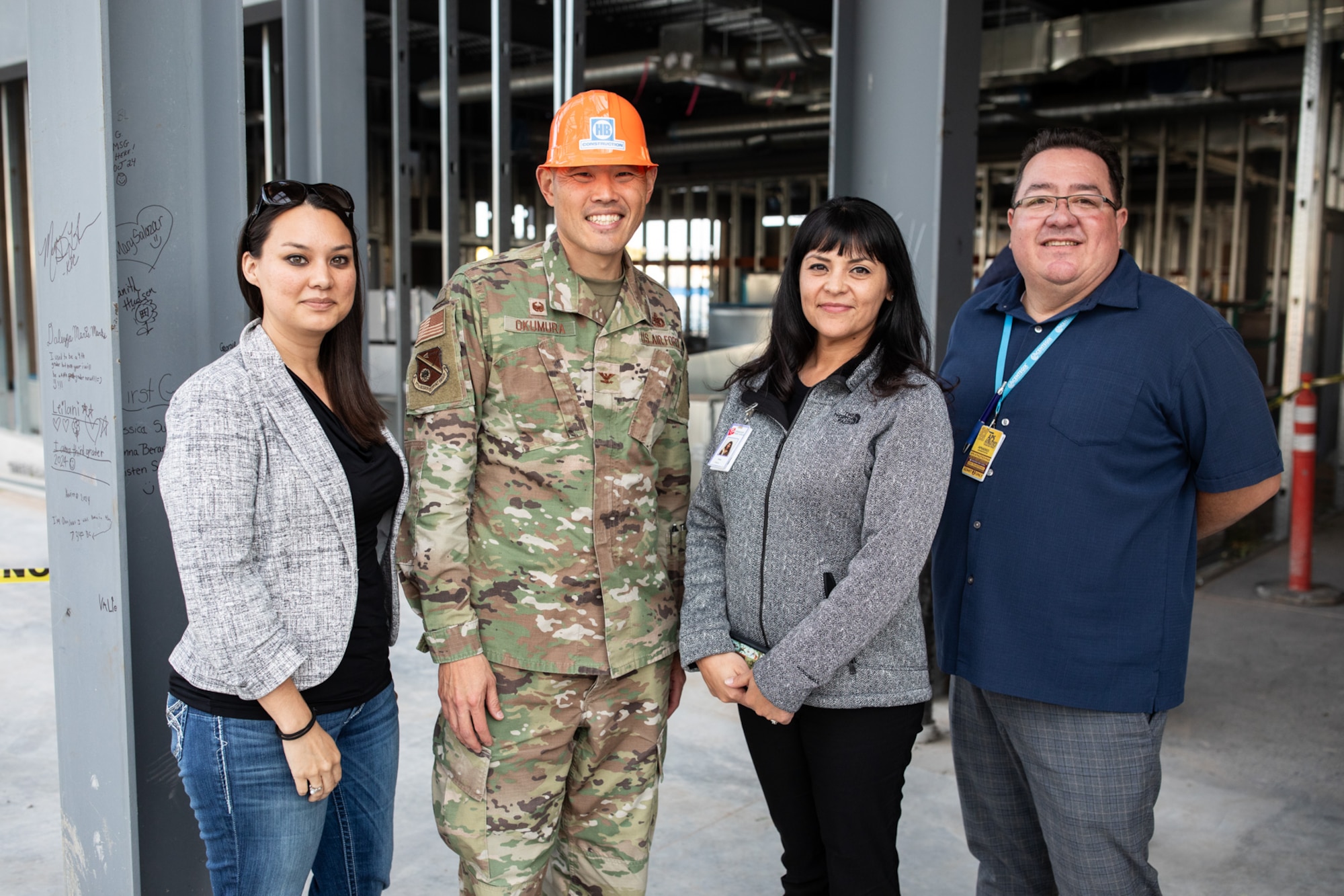 Four people pose for photo in construction site for new elementary school