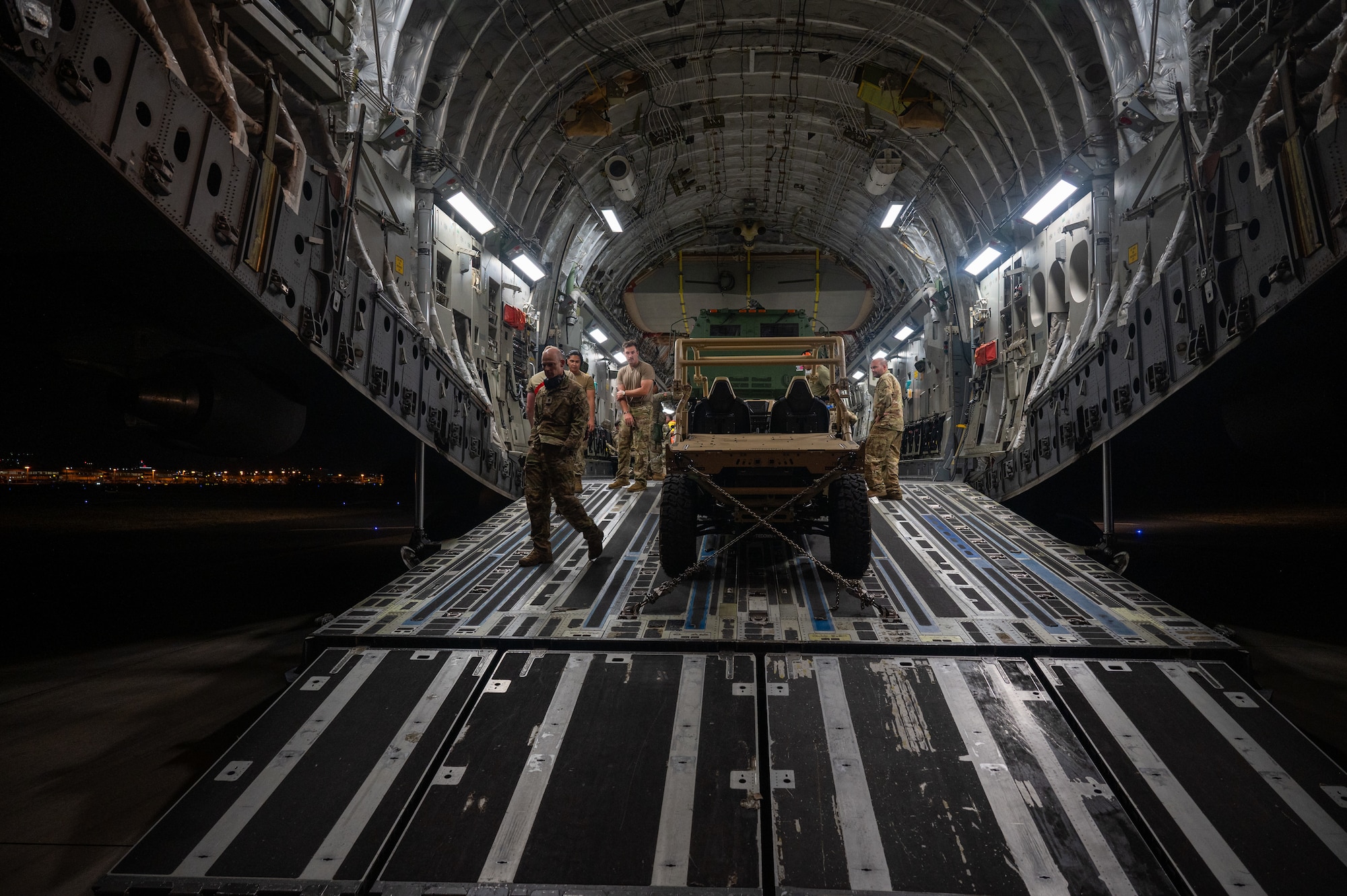 Airmen secure vehicles inside the back of a C-17 Globemaster III aircraft.