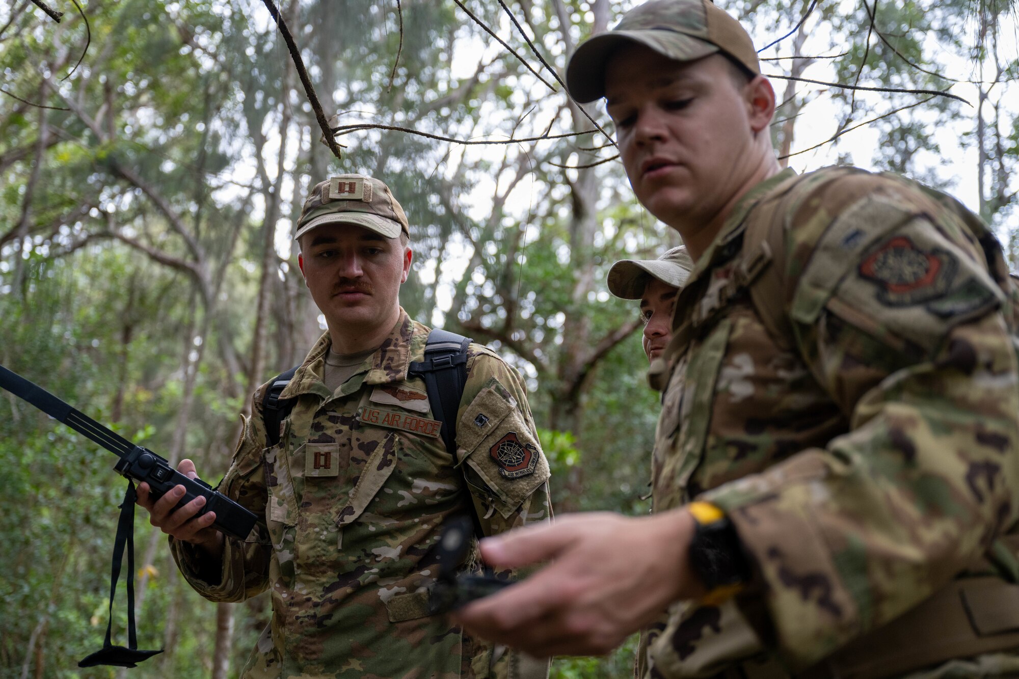 U.S. Air Force members look down at their radios while outside.