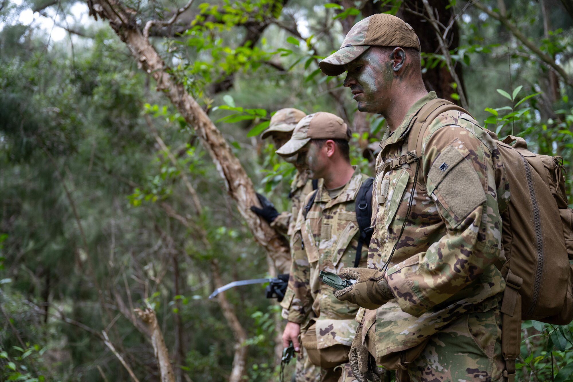 U.S. Airmen wearing camo face paint stand outside.