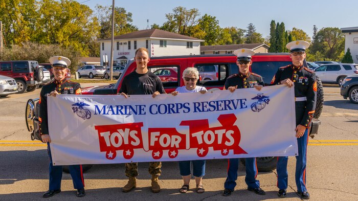 U.S. Marines with Recruiting Station Milwaukee pose for a photo with Sherry Bright the Jones County Toys for Tots coordinator after the Anamosa Pumpkin Fest parade in Anamosa, Iowa, Oct. 5, 2024. Marines and poolees participated in the parade to support the local Toys for Tots program and to increase Marine Corps awareness in the local area. (U.S. Marine Corps photo by Cpl. Collette Hagen)