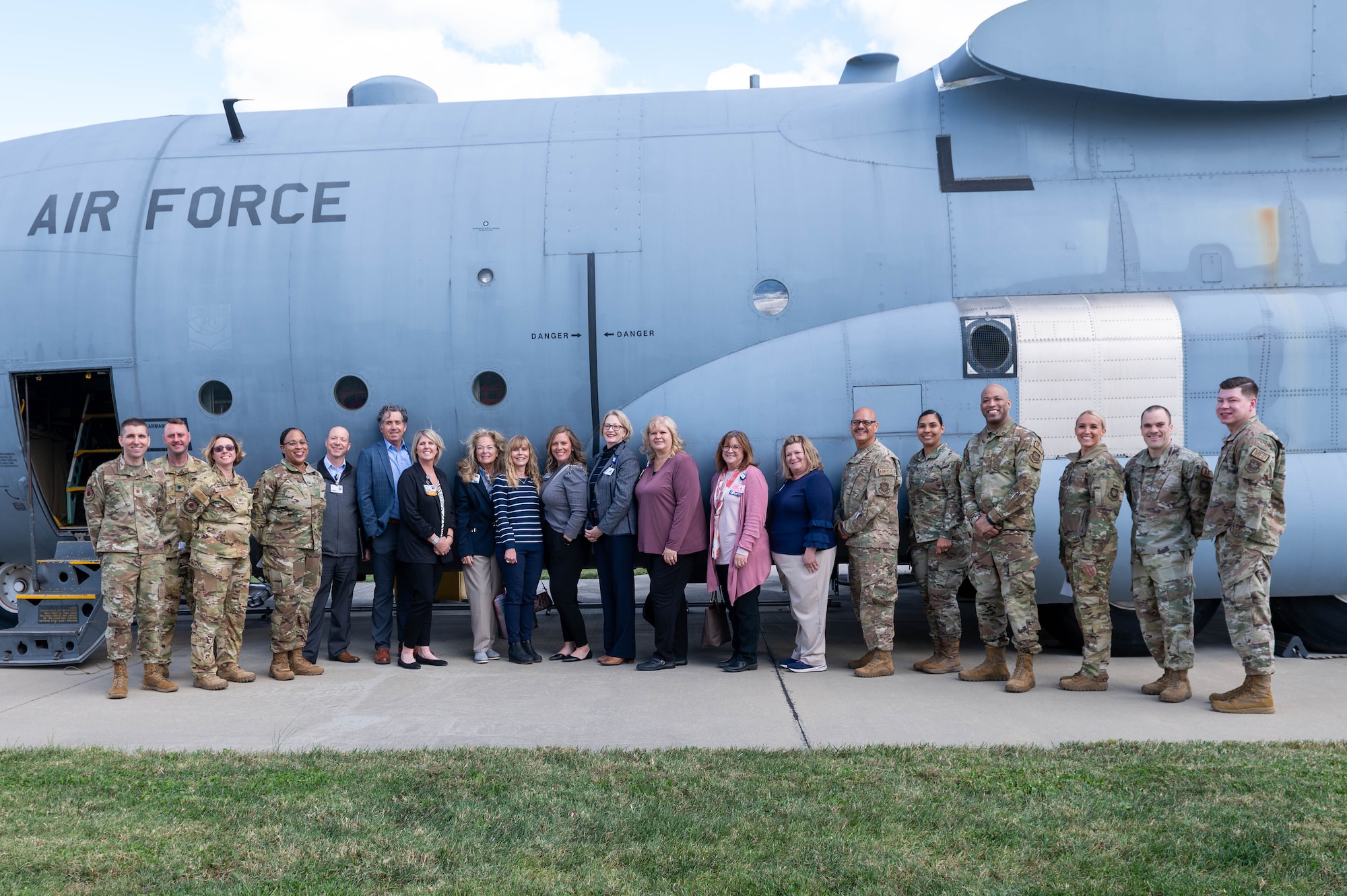 Air Force airmen and medical staff stand in front of plane for a photo.
