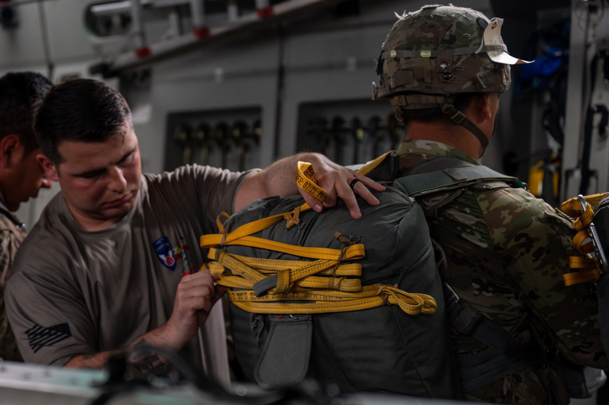A Soldier who is a jump master puts his fingers through the laces of a parachute to ensure safety of the solider who will be jumping.