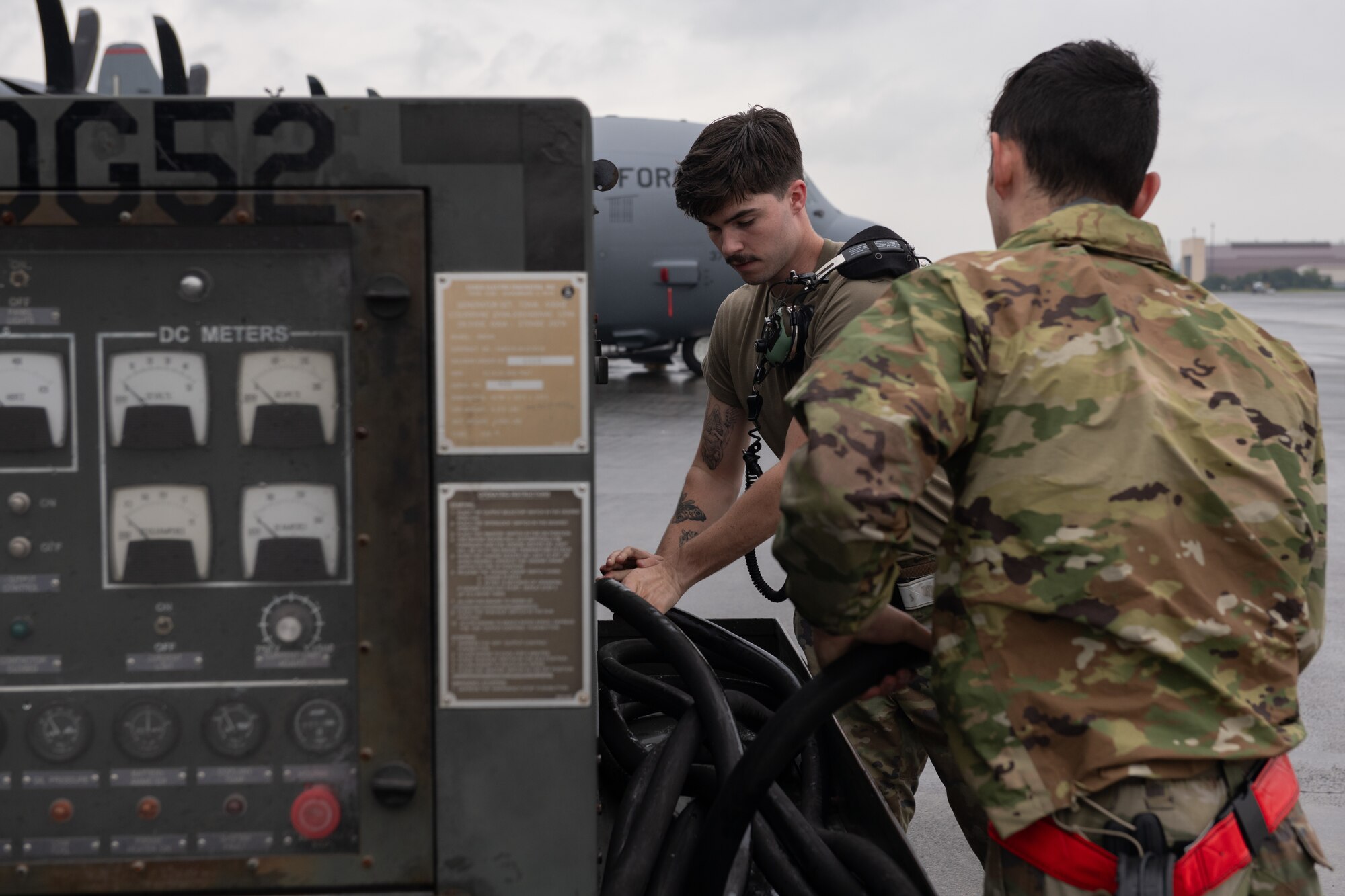 Two Airmen disconnect a generator from a C-130J aircraft.