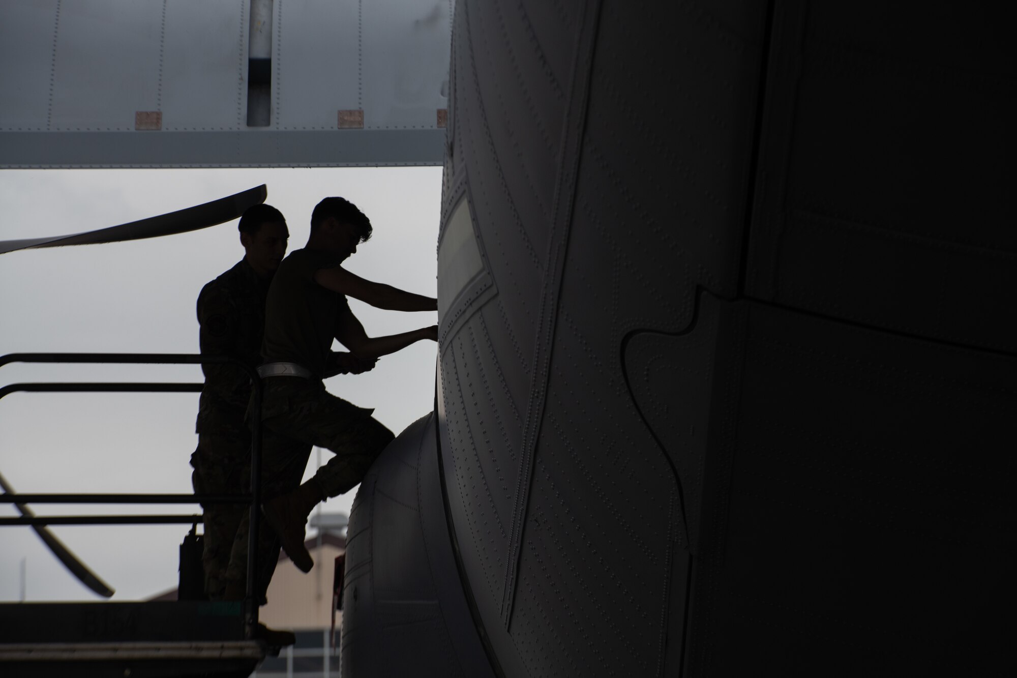 Two Airmen remove parts from a C-130J Super Hercules aircraft.
