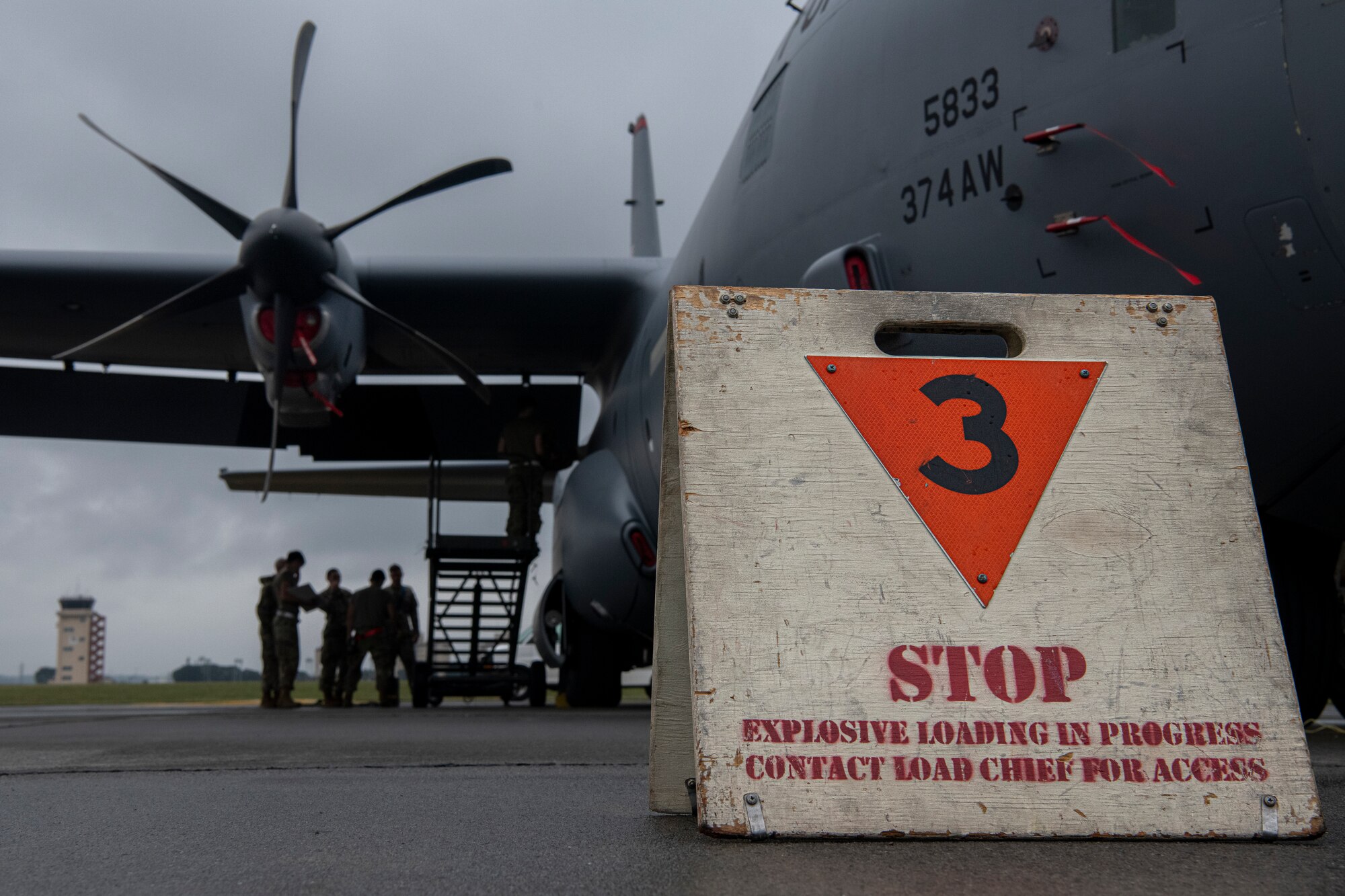 A warning sign is displayed as airman temporarily load chaff and flares into an aircraft.