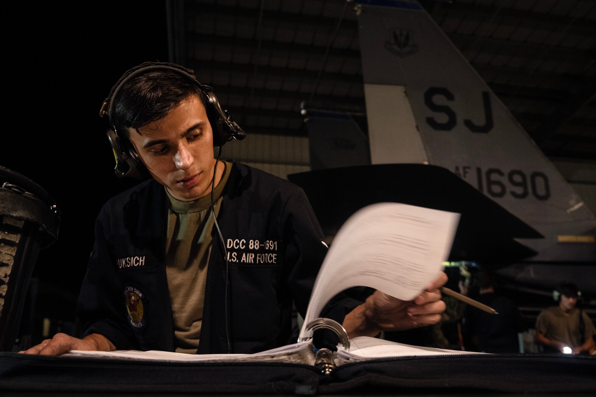 Senior Airman Britton Puksich, 334th Fighter Generation Squadron dedicated crew chief, reviews information while performing maintenance on an F-15E Strike Eagle.