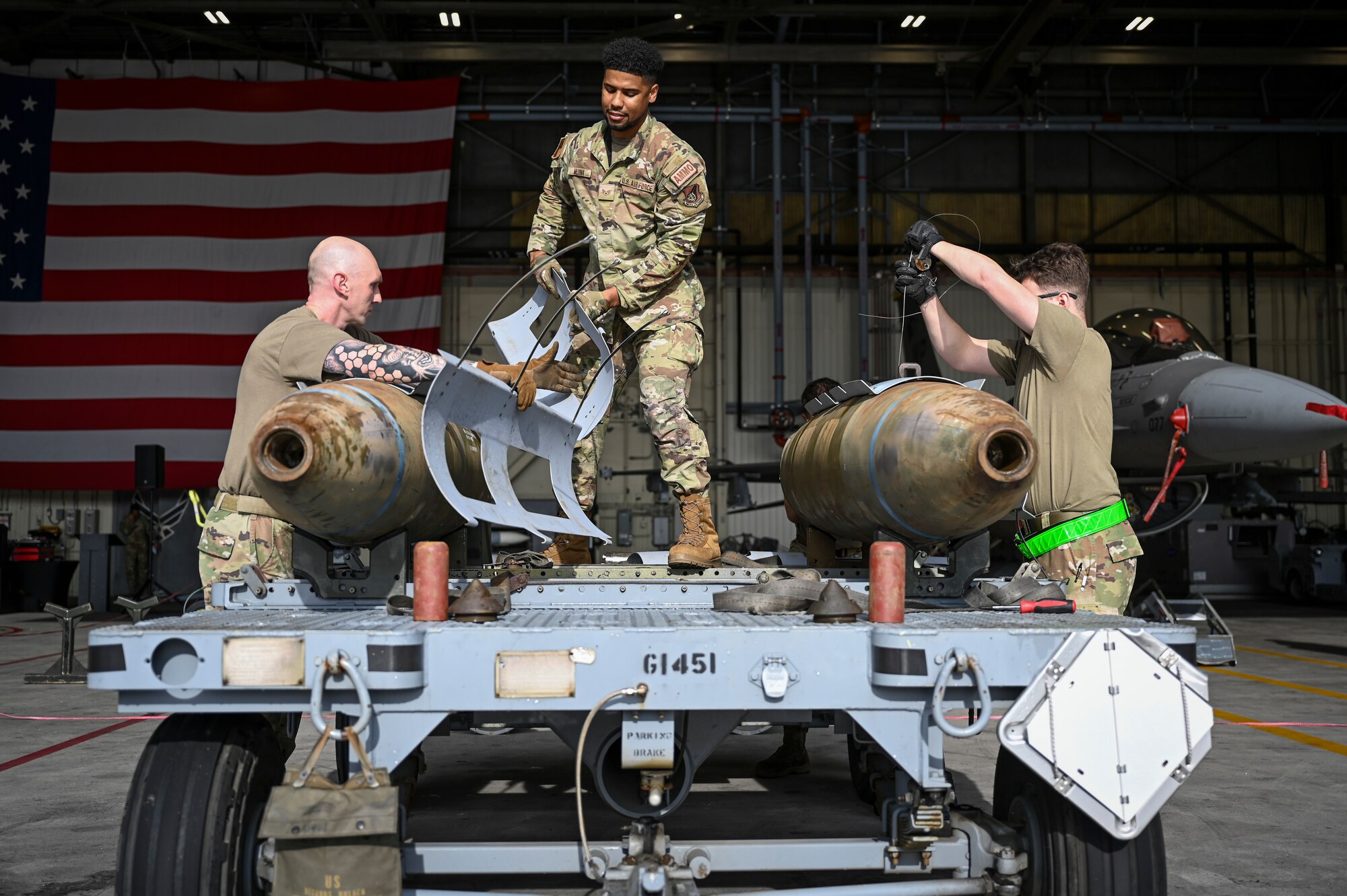U.S. Air Force Staff Sgt. Benjamin Davis, left, Staff Sgt. Hector Medina, middle, 8th Maintenance Squadron combat plans supervisors, and Airman 1st Class Hunter Johnson, right, 8th MXS munitions controller, prepare munitions for loading during the 2024 3rd Quarter Dedicated Crew Chief and Load Crew Competition.