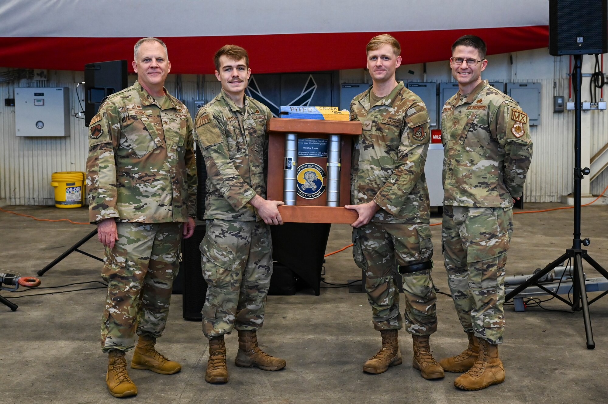 U.S. Air Force Col. Casey Crabill, far left, 8th Maintenance Group commander, and Chief Master Sgt. Nathan Bouchard, far right, 8th MXG command chief, congratulate Senior Airman Mason Schumacher center left, and Staff Sgt. Logan Stacy, center right, 8th Aircraft Maintenance Squadron crew chiefs, for winning Dedicated Crew Chief of the Quarter during the 2024 3rd Quarter Dedicated Crew Chief and Load Crew Competition.