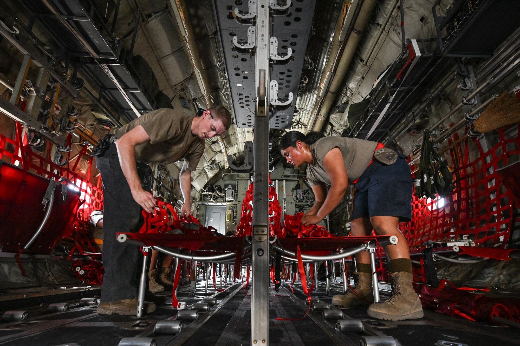 Two service members set up seats on an aircraft.