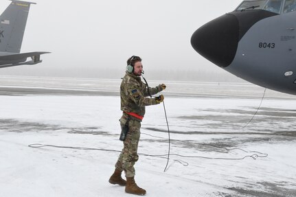 Master Sgt. Cody Albert of the 168th Aircraft Maintenance Squadron communicates to his wingmen while preparing the KC-135 Stratotanker for an aerial refueling flight during a communications out exercise at Eielson Air Force Base, Alaska, Oct. 18, 2024. The exercise was designed to sharpen skills in operating without radios.