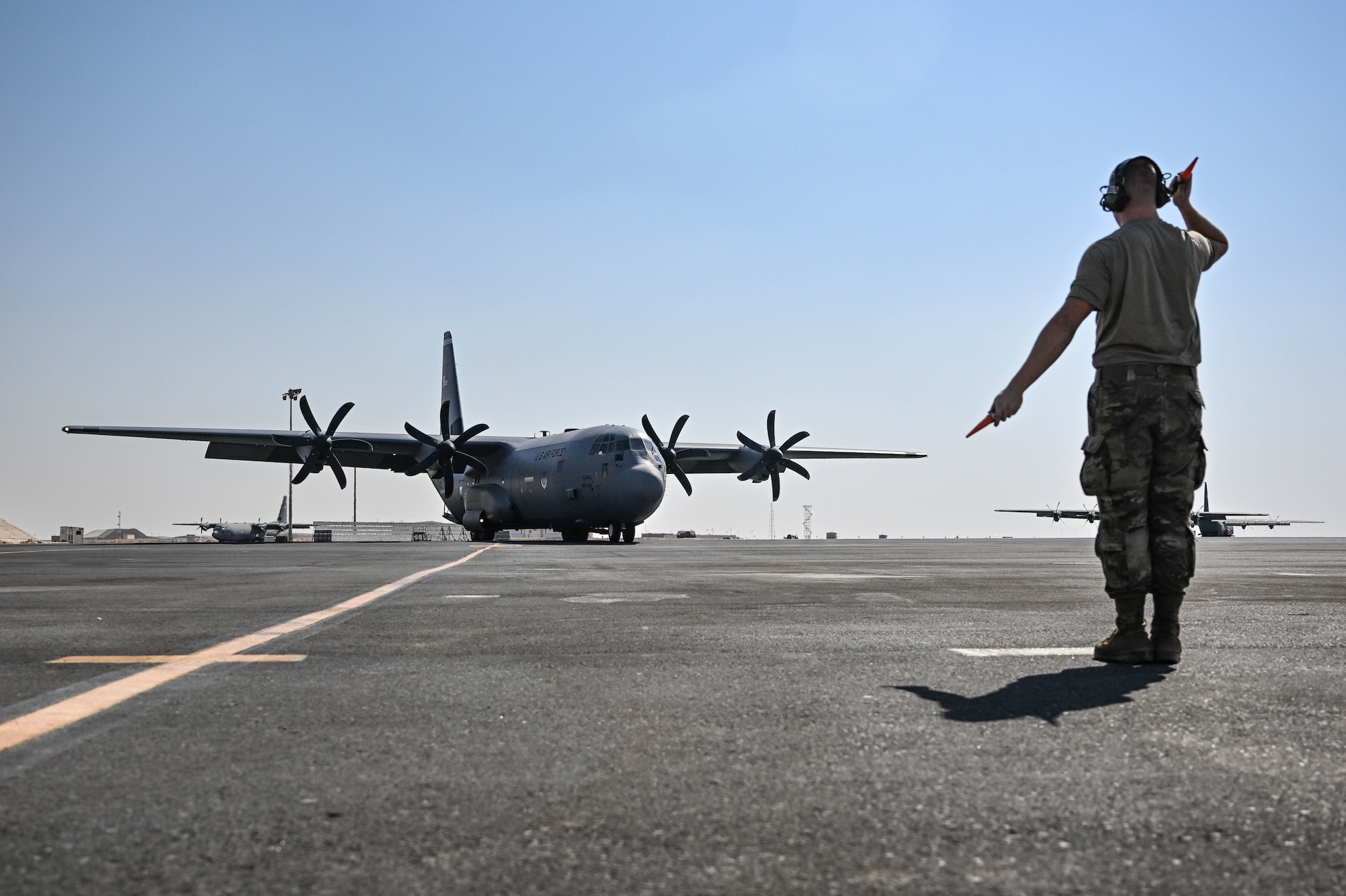 A crew chief marshals in an aircraft on the flightline.