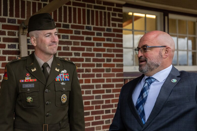 A man in a military uniform speaks to a man in a suit.
