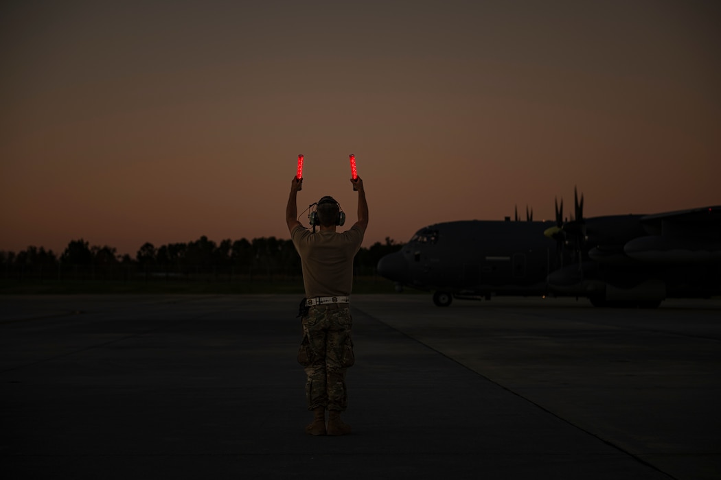 An airman marshals an aircraft onto the flight line