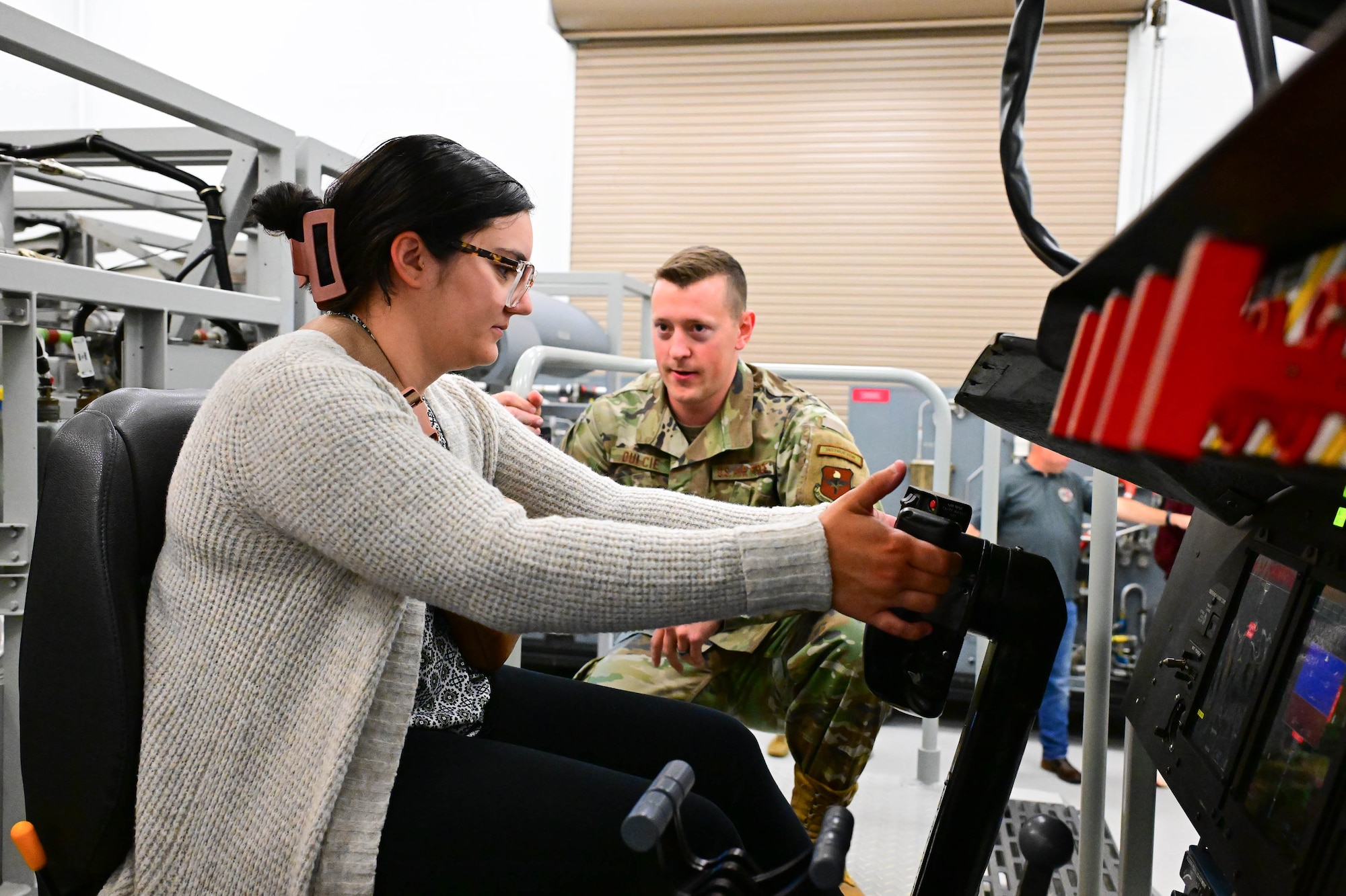 U.S. Air Force Staff Sgt. Jacob Dulcie, 373rd Training Squadron, Detachment 3 C-5M Super Galaxy maintenance instructor, shows Keri Knorr, Delaware Municipal Electric Corporation administrative assistant, how to operate a flight controls system trainer at Dover Air Force Base, Delaware, Oct. 21, 2024. Team Dover provided the DEMEC staff a hands-on tour to familiarize them with the base mission and capabilities. (U.S. Air Force photo by Mauricio Campino)
