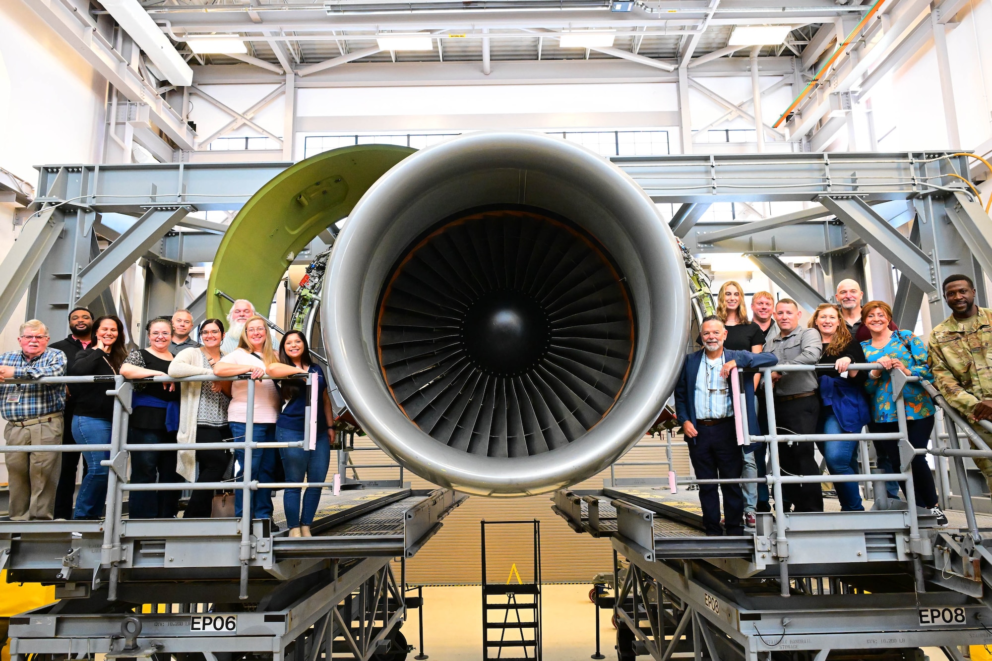 Delaware Municipal Electric Corporation staff pose with a C-5M Super Galaxy engine maintenance simulator during a tour at Dover Air Force Base, Delaware, Oct. 21, 2024. Team Dover provided the DEMEC staff a hands-on tour to familiarize them with the base mission and capabilities. (U.S. Air Force photo by Mauricio Campino)
