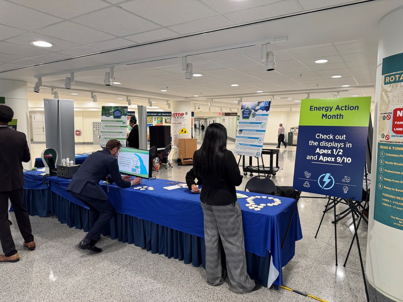 A man and a woman prepare static displays and information pamphlets at a table.