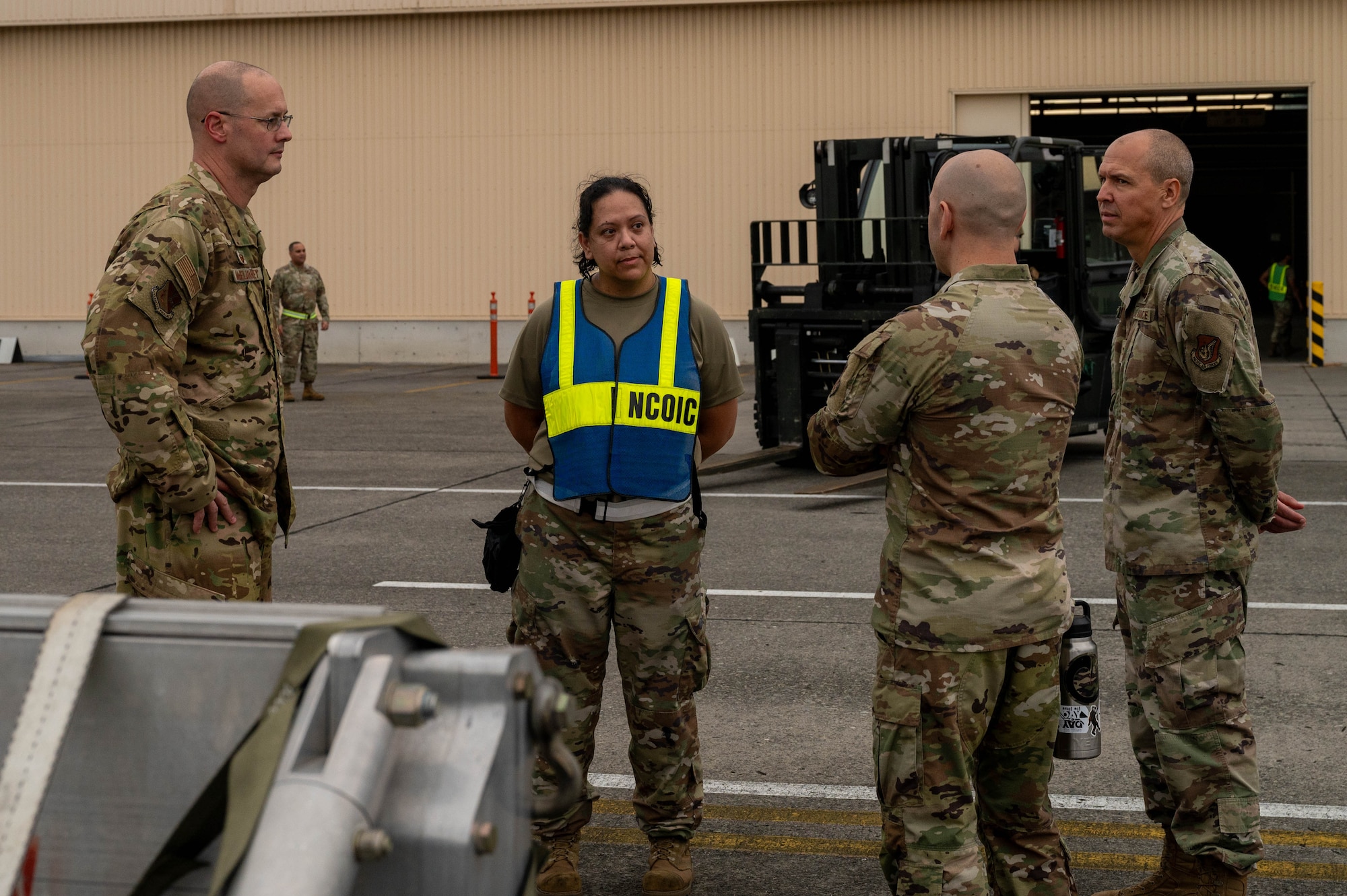 Four military members stand in a square talking to each other.