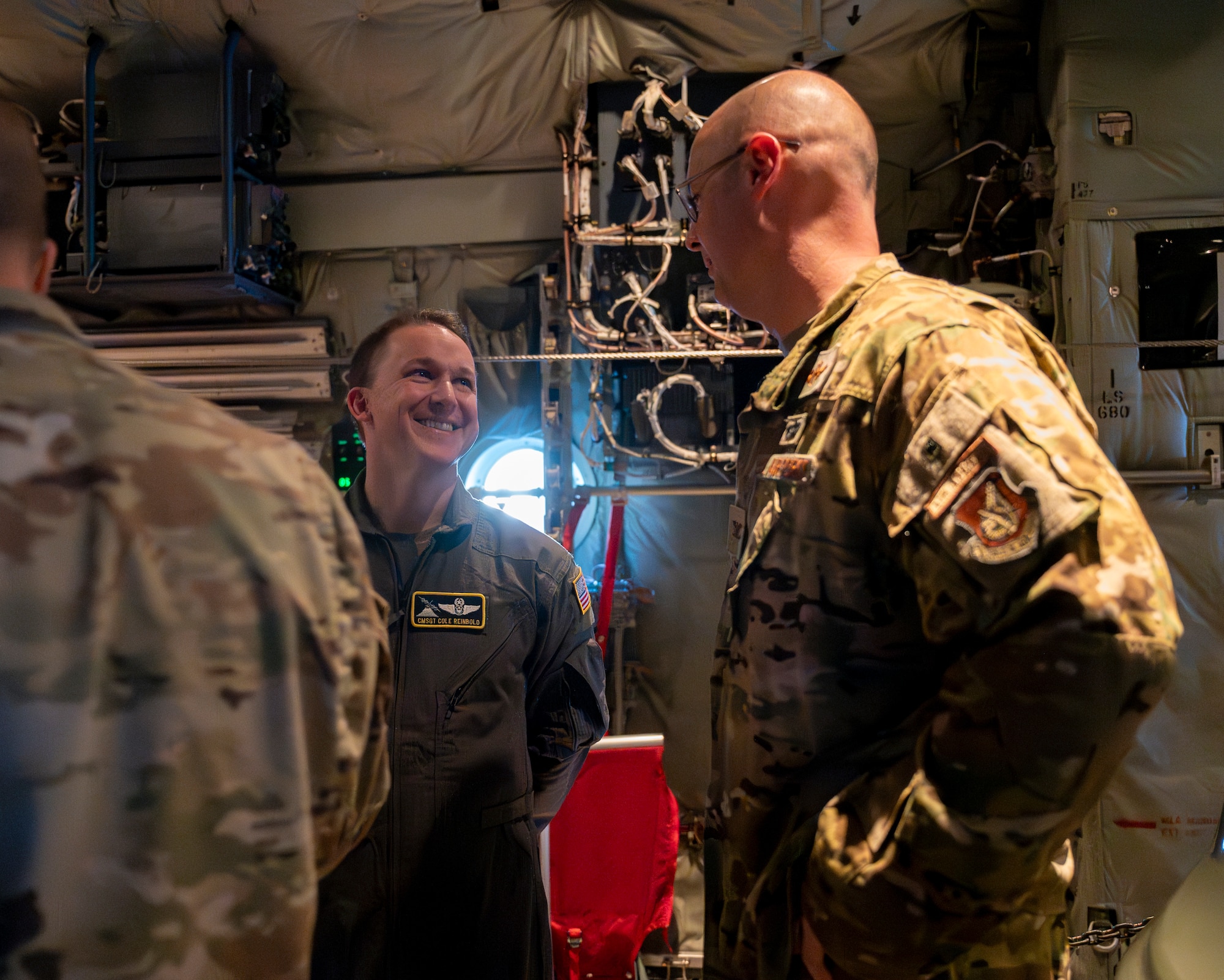Two military members speak inside of an aircraft.