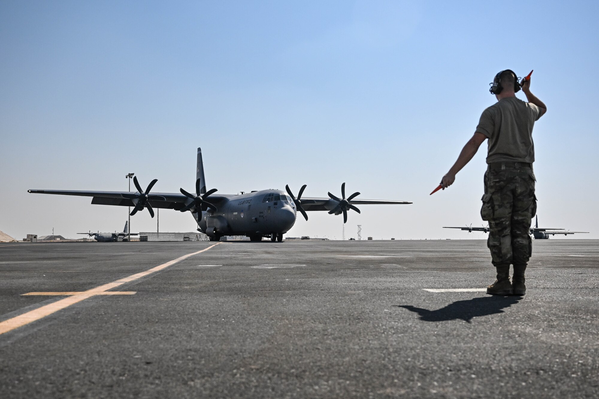 A crew chief marshals in an aircraft on the flightline.