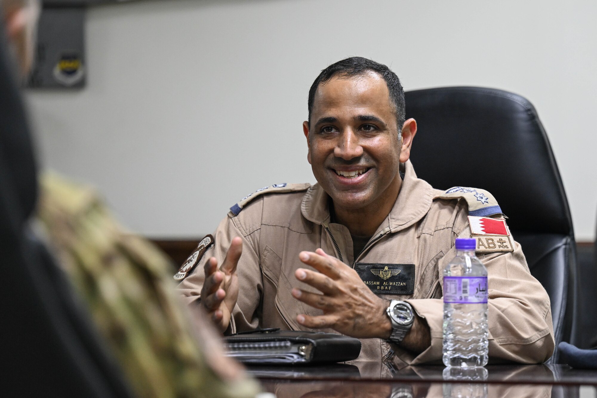 A person is smiling while sitting in a conference room.