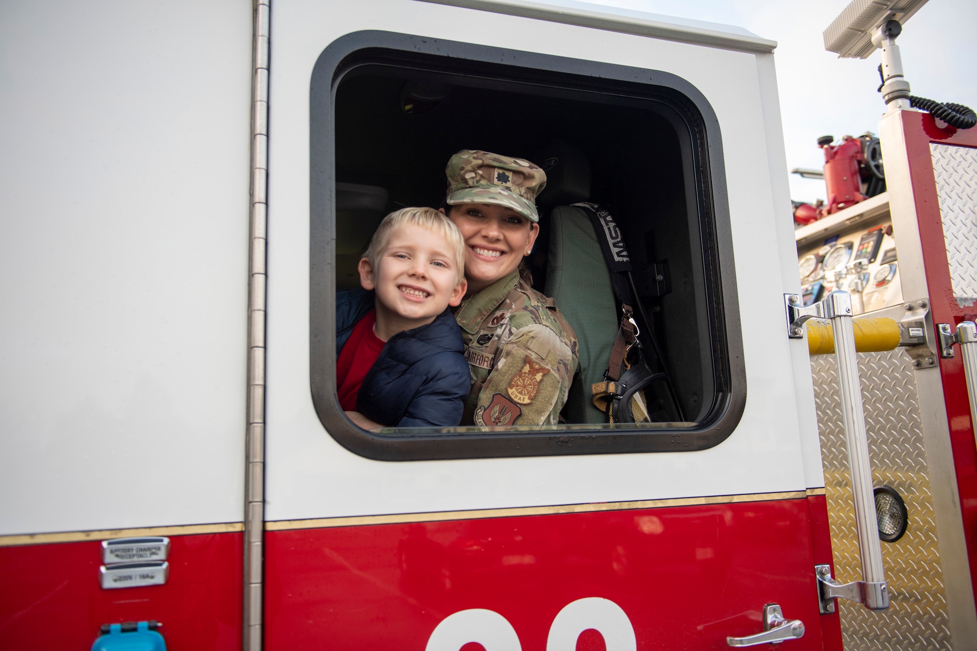 The fire marshal sits with her son in a firetruck.