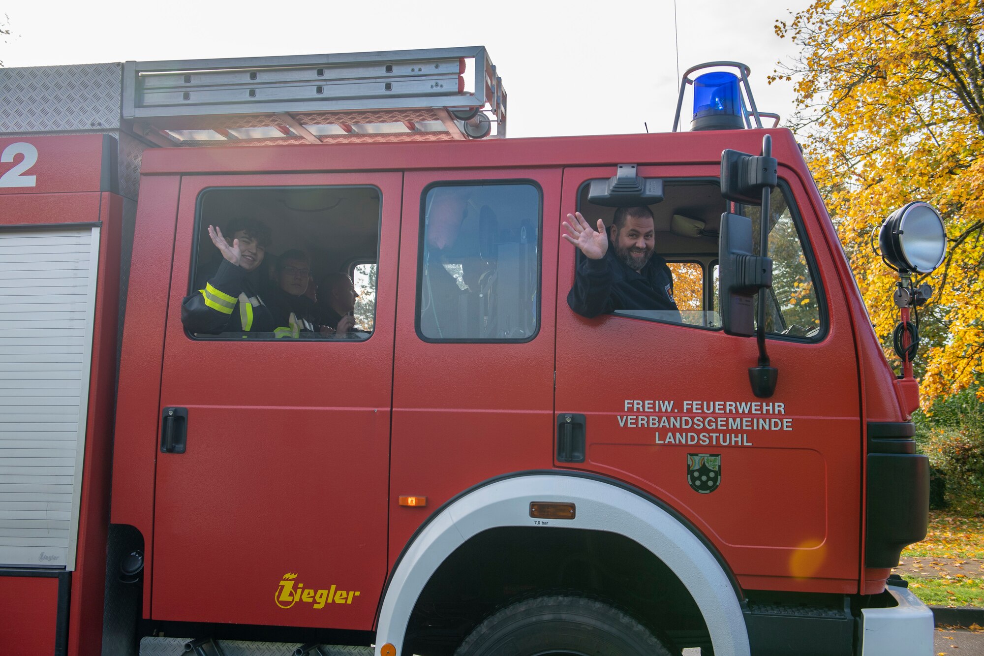 People ride in a fire truck and wave.