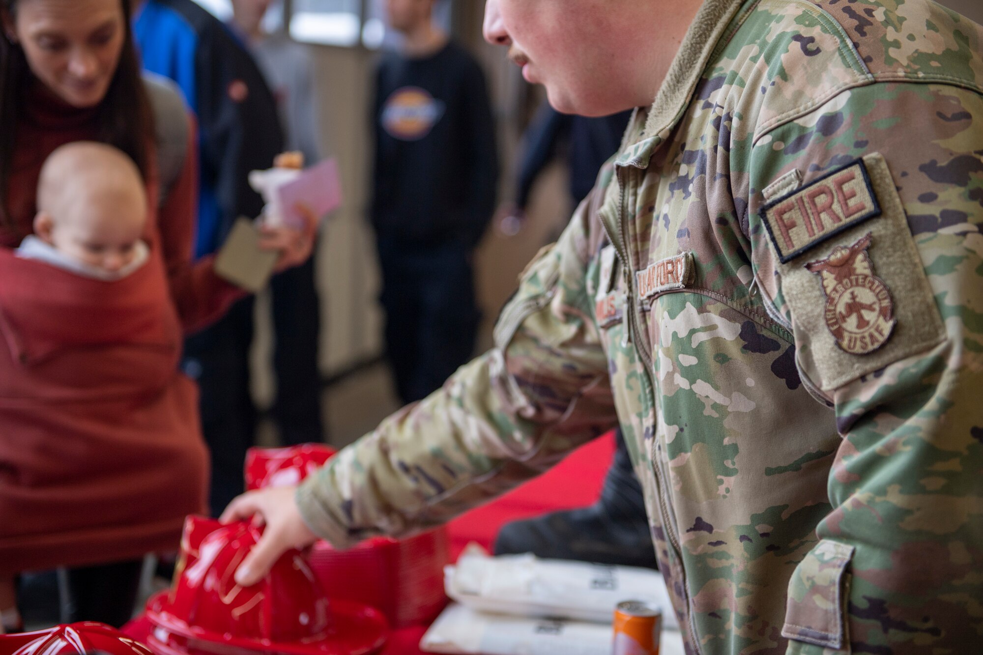 A firefighter hands out plastic hats to kids at an event.