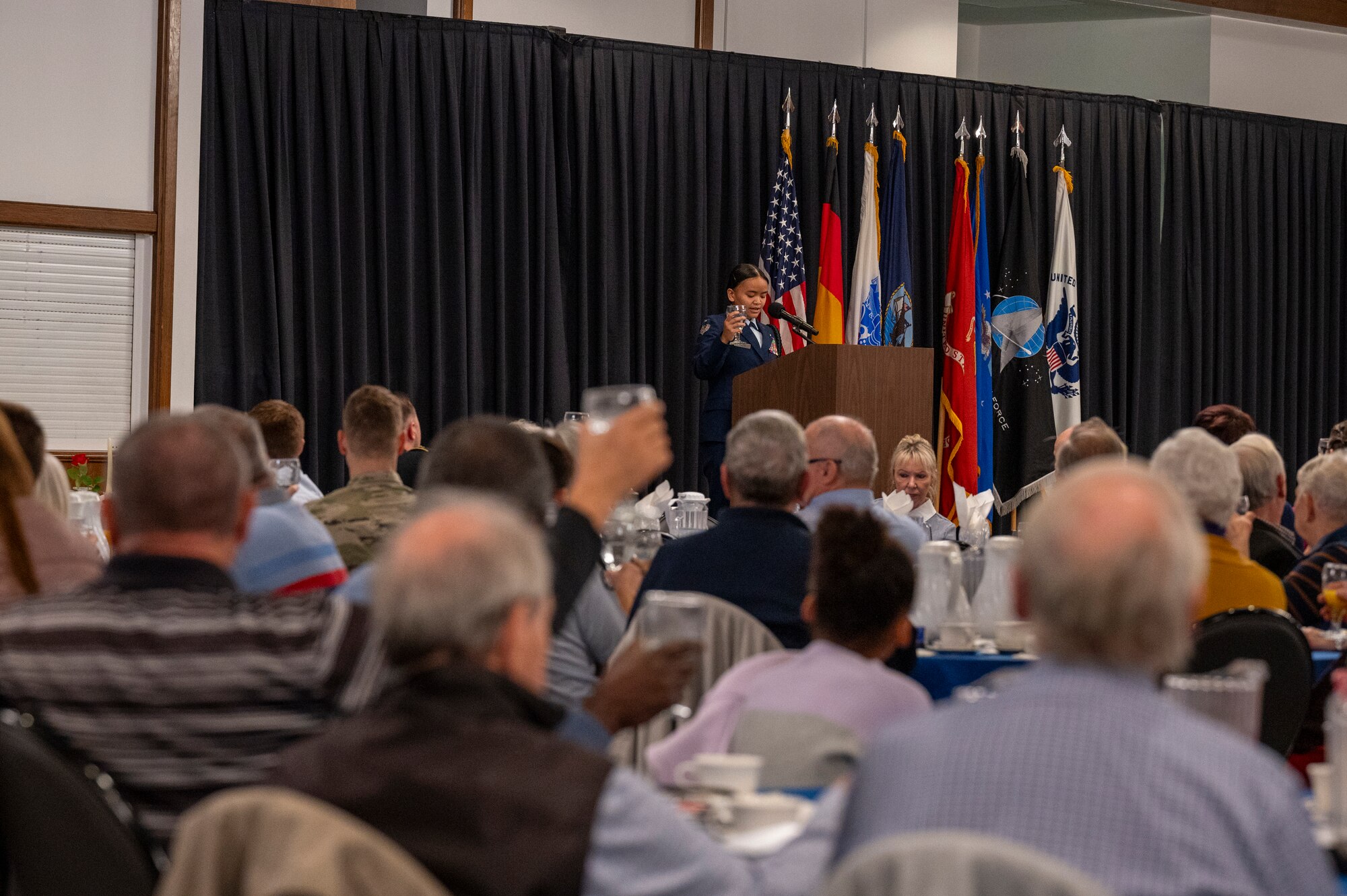 A Ramstein High School Junior Reserve Officers’ Training Corps member raises a water glass in a toast to honor America’s POW/MIAs during the 2024 Military Retiree Appreciation Day event at Ramstein Air Base, Germany, Oct. 21, 2024.