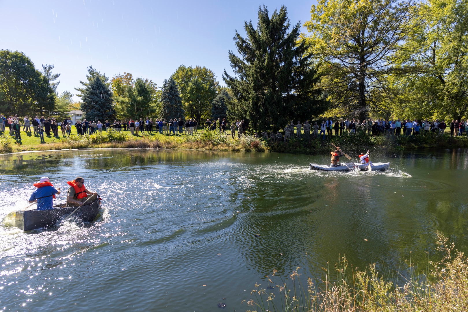 Cardboard boats make their way down the length of a pond.