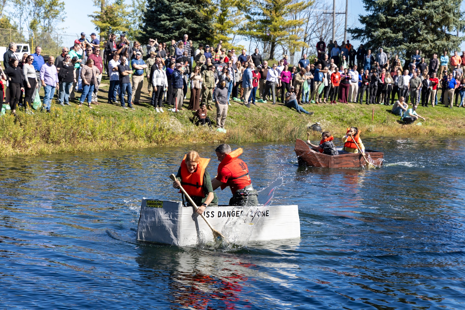 Cardboard boats make their way down the length of a pond.