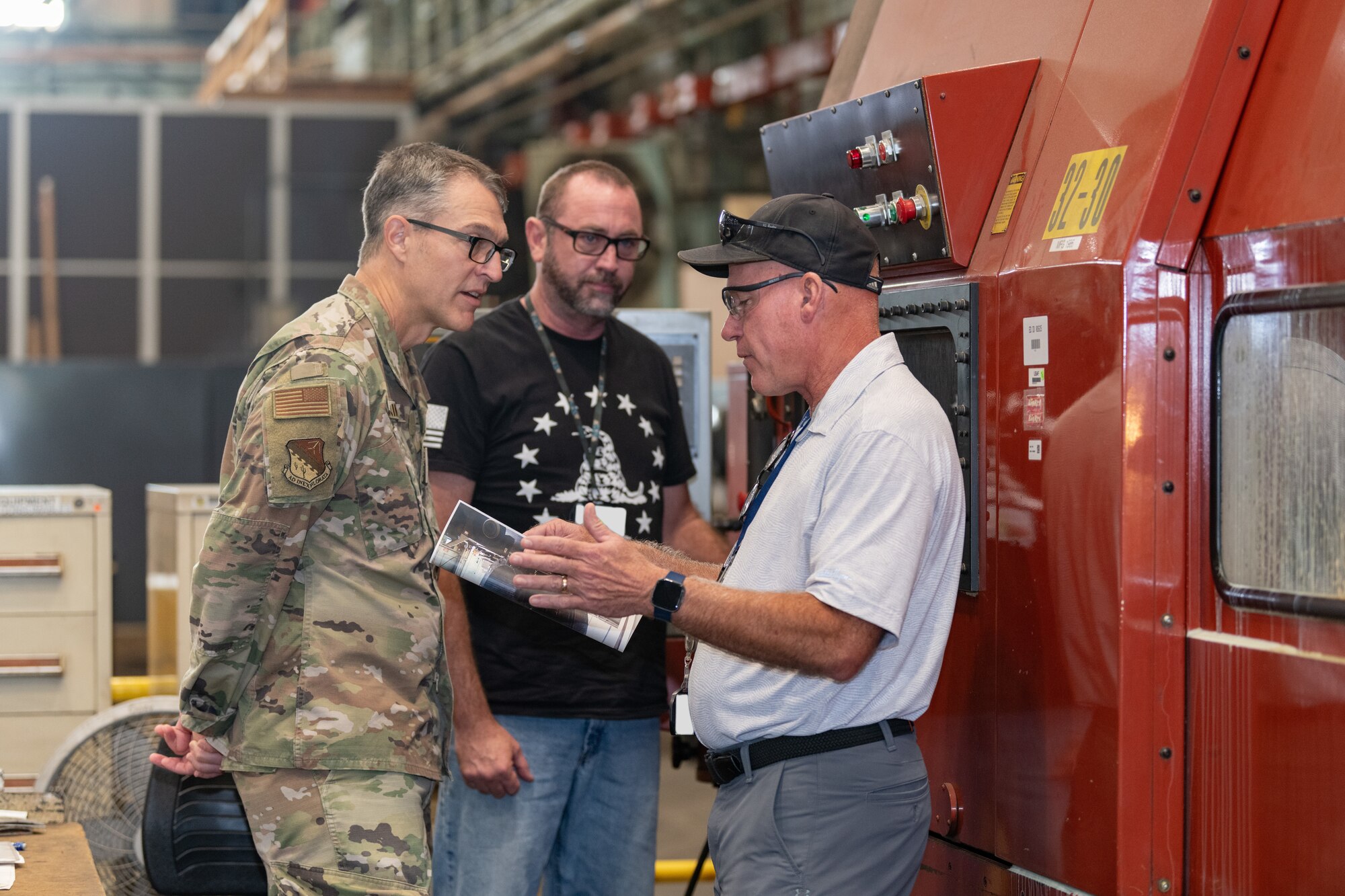 Maj. Gen. Scott A. Cain, Air Force Test Center commander, left, meets with Brad Reid, manufacturing services deputy manager for the Arnold Engineering Development Complex Test Operations and Sustainment contractor, right, and aerospace precision machinist Craig Jones in the Arnold Air Force Base Model and Machine Shop during a recent visit to Arnold AFB, Tenn., headquarters of AEDC. Cain, a previous AEDC commander, visited Arnold Oct. 2-3, 2024, to tour the installation, meet with base personnel and observe operations at Arnold. (U.S. Air Force photo by Keith Thornburgh) (This image was altered by obscuring badges for security purposes)