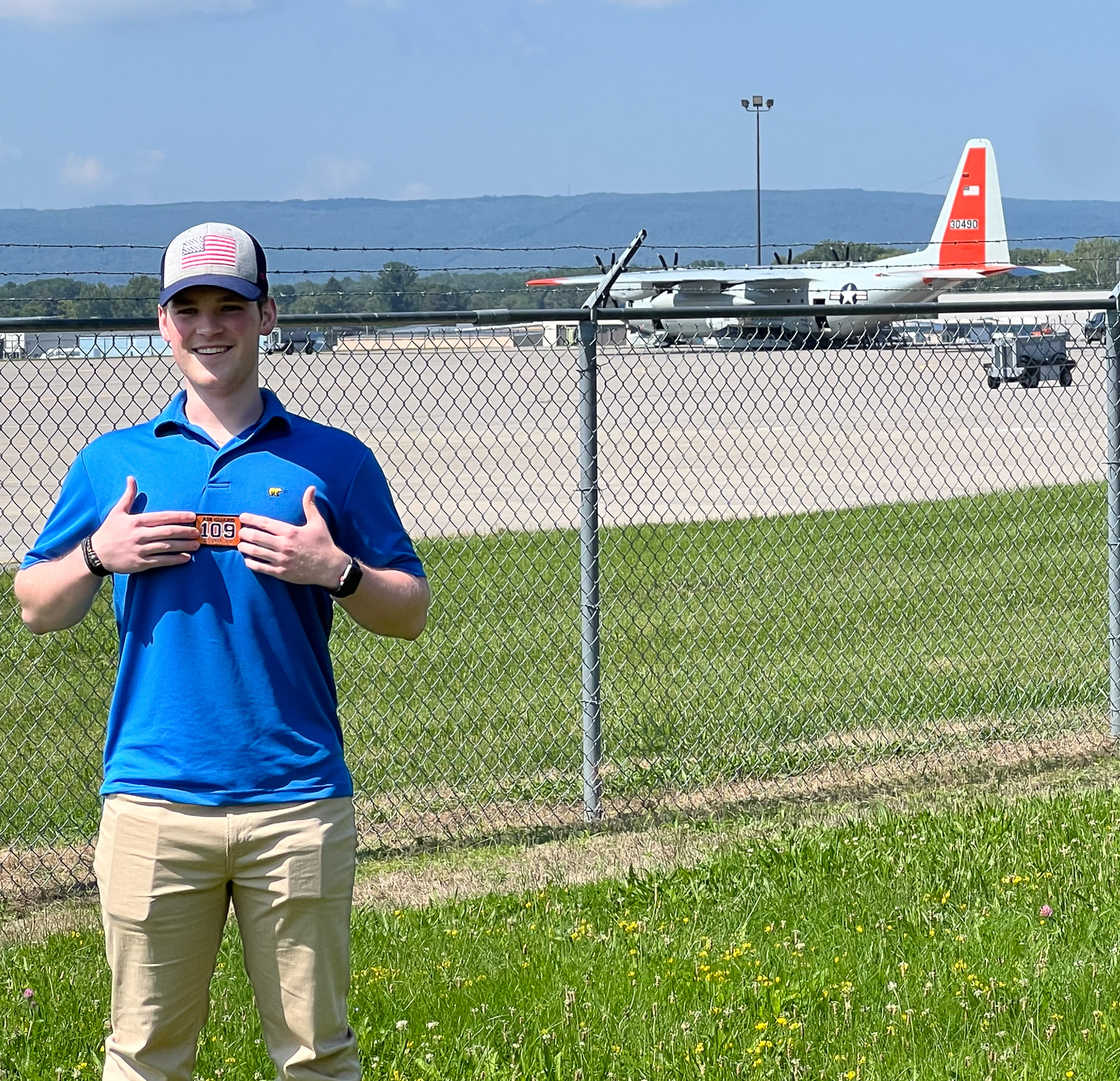 Brendan Murphy, a new recruit, poses with a 109th Airlift patch in front of the flightline at the 109th Airlift Wing, Scotia, NY, on August 27, 2024. Murphy took a similar photo when he was young, with a patch given to him by a member of the 109th Airlift Wing.